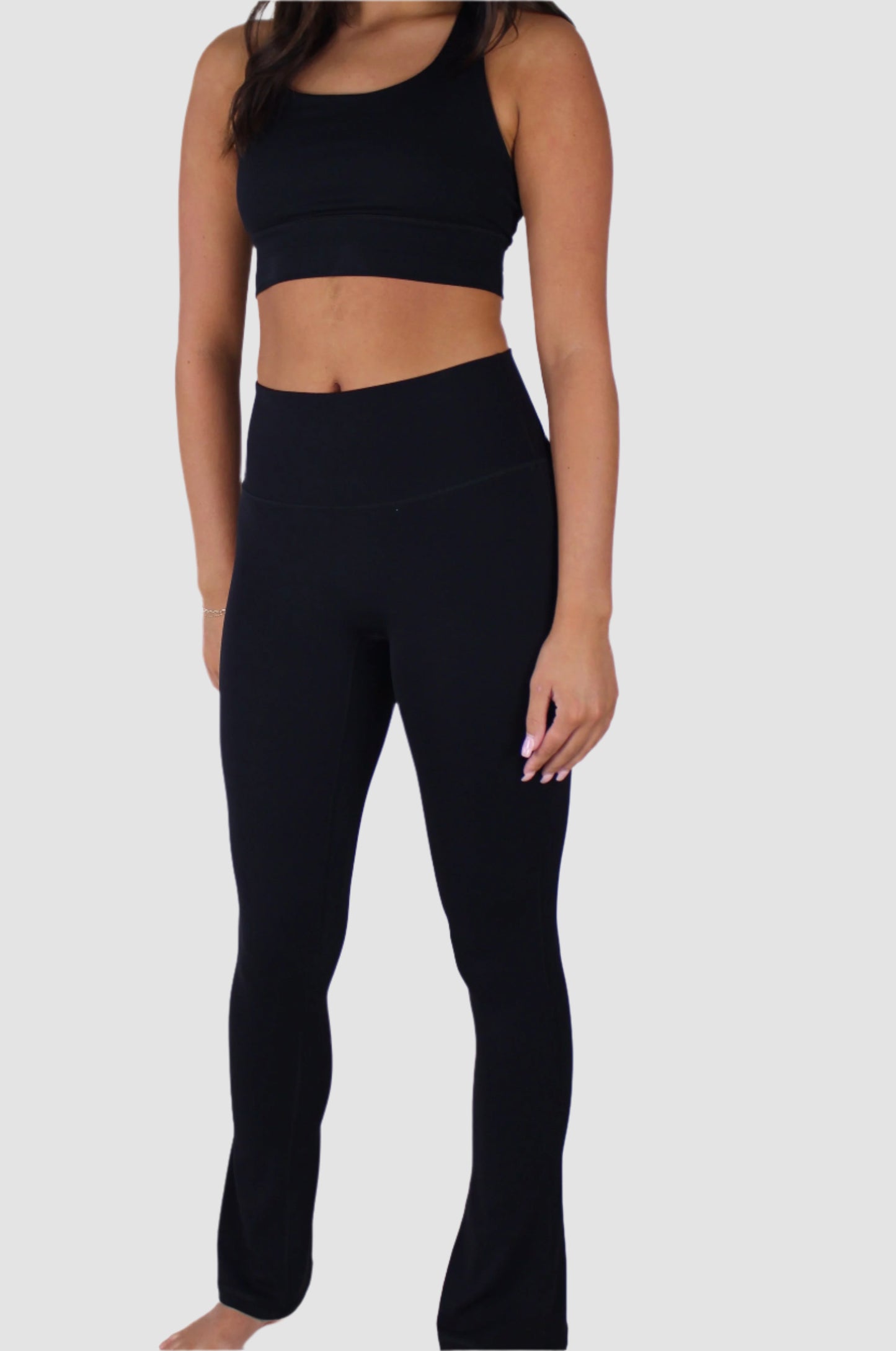 Full body front view of black Aivvia Athletics high-waisted flare pants styled with sports bra.