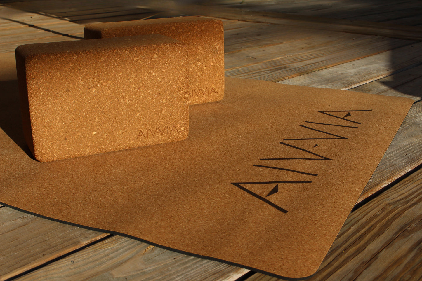 Close-up of two cork yoga blocks resting on a cork yoga mat with sunlight highlighting the texture.