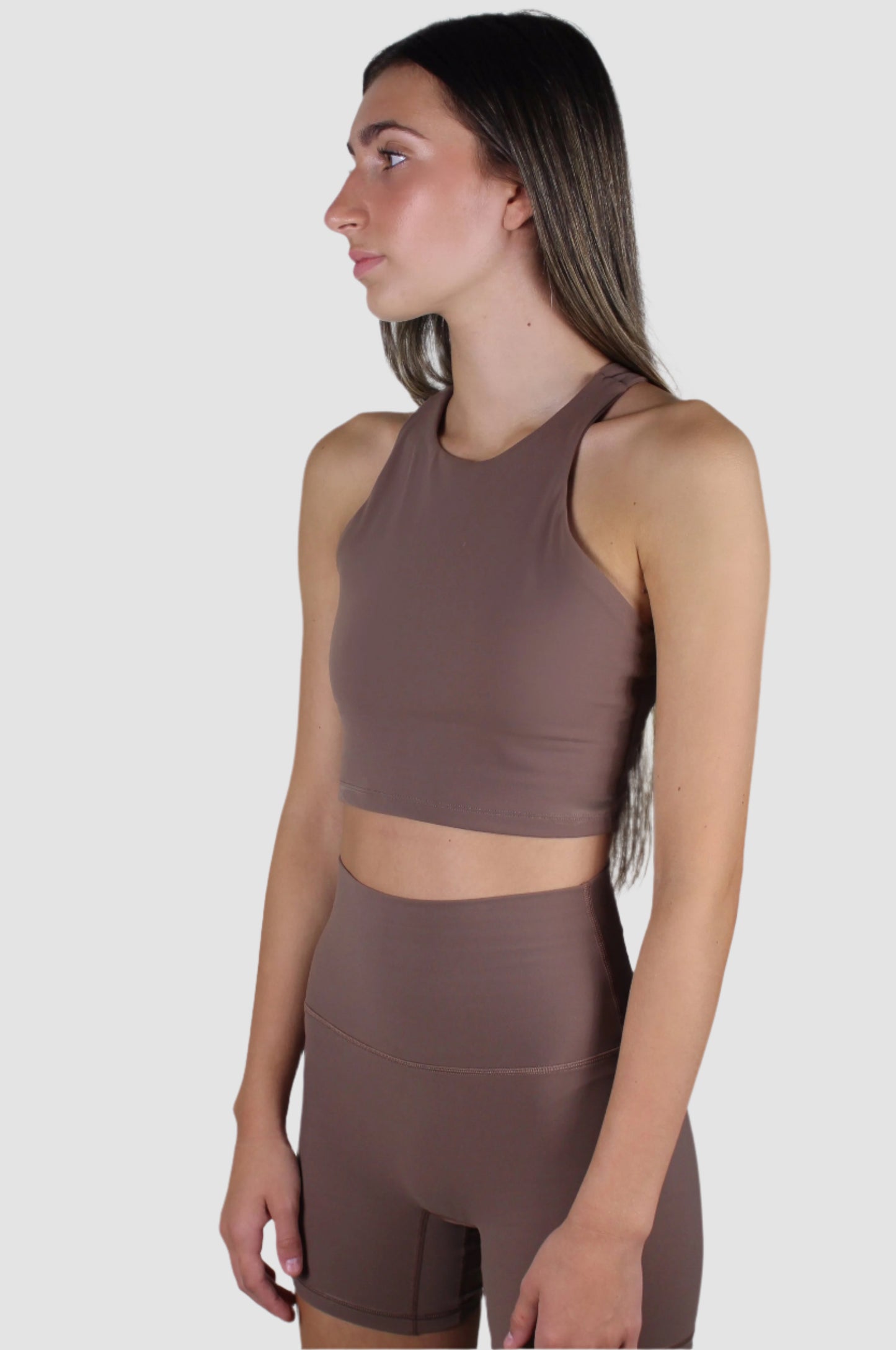 Side profile of the chocolate brown activewear set, highlighting the sleek, form-fitting design of both the top and shorts.
