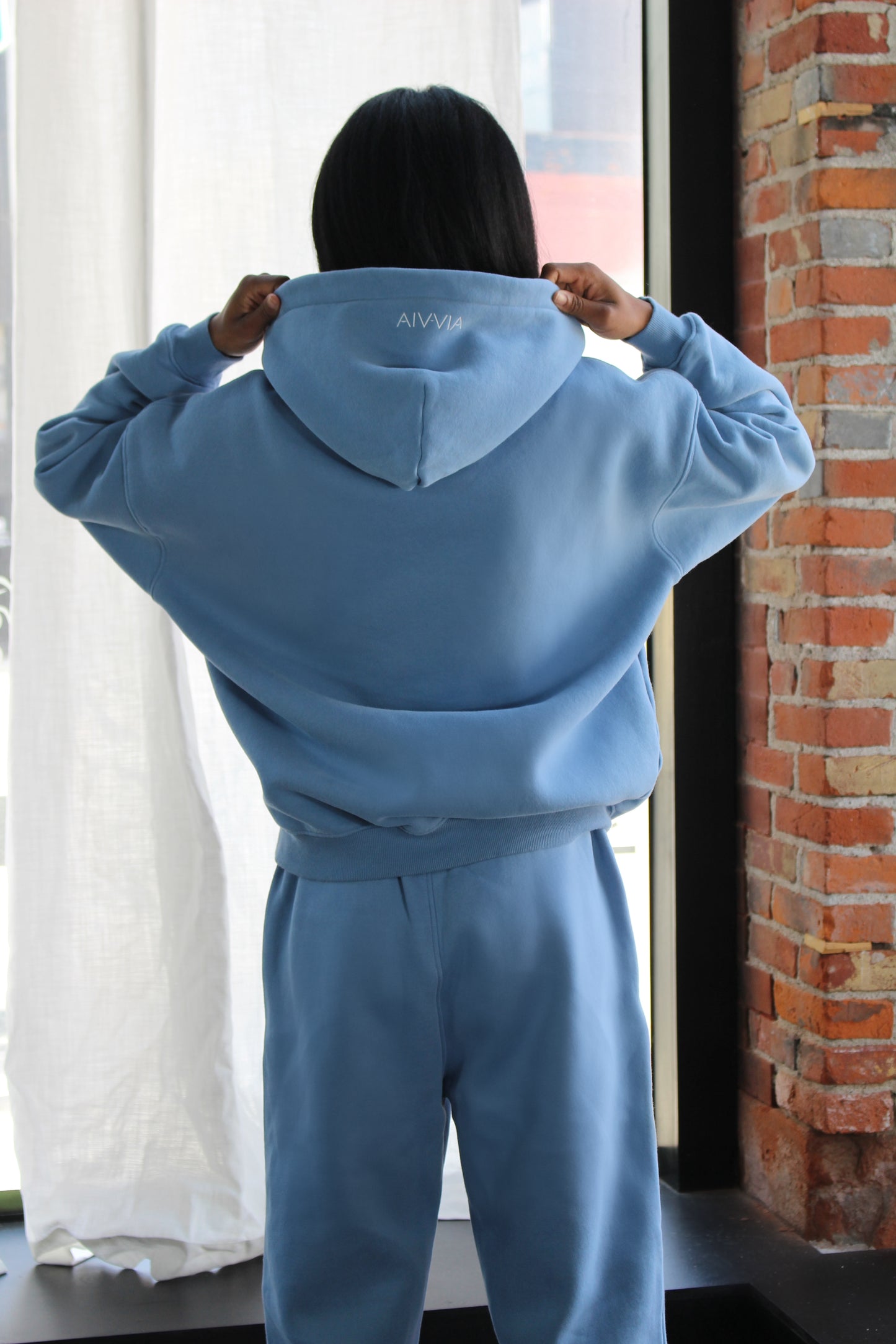 Back view of light blue Aivvia Athletics sweatpants with relaxed fit and seamless comfort; styled with matching hoodie.