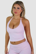 Woman wearing a pink sports bra and leggings against a plain background