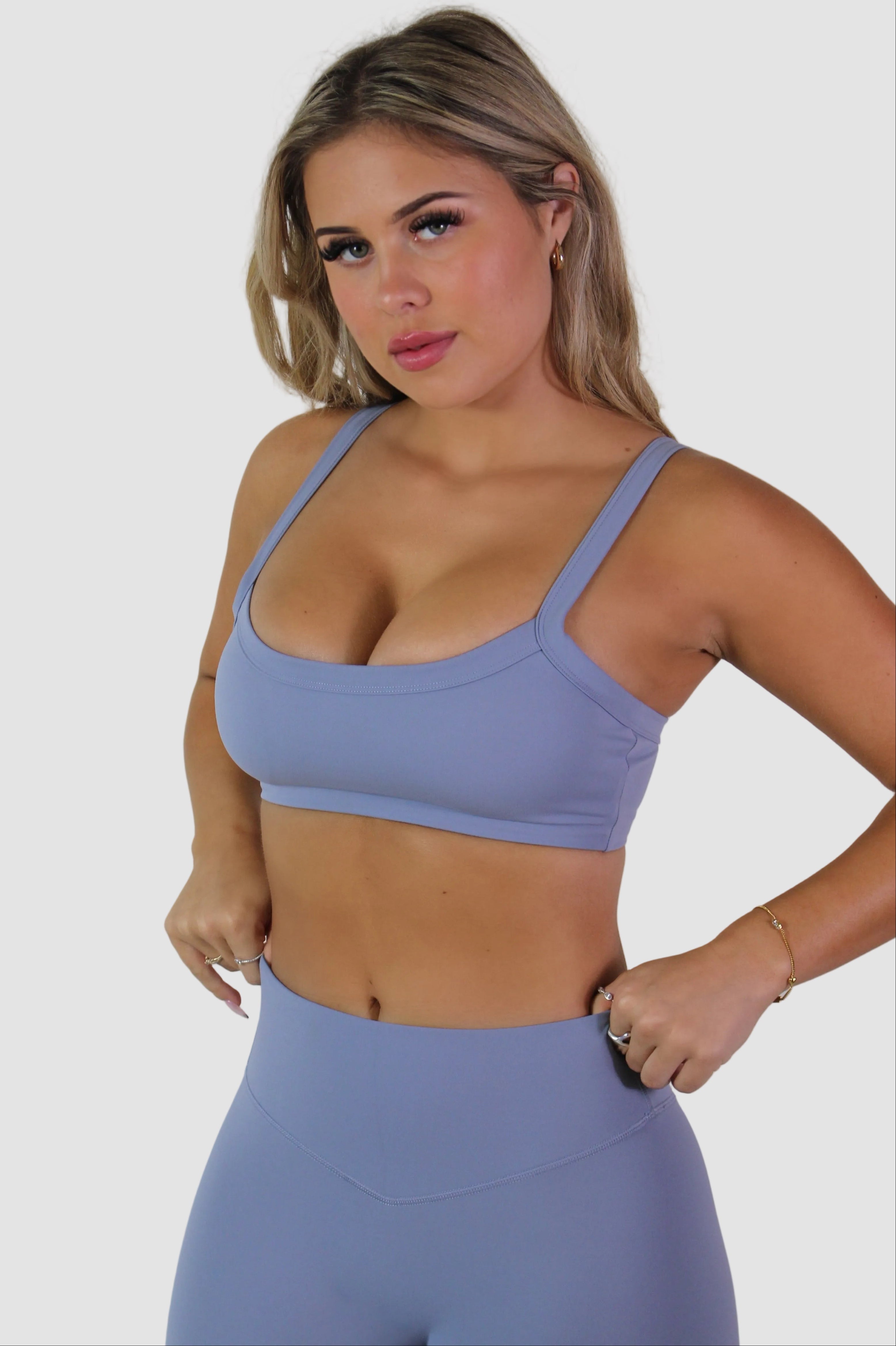 Woman wearing a light blue sports bra and leggings against a plain background
