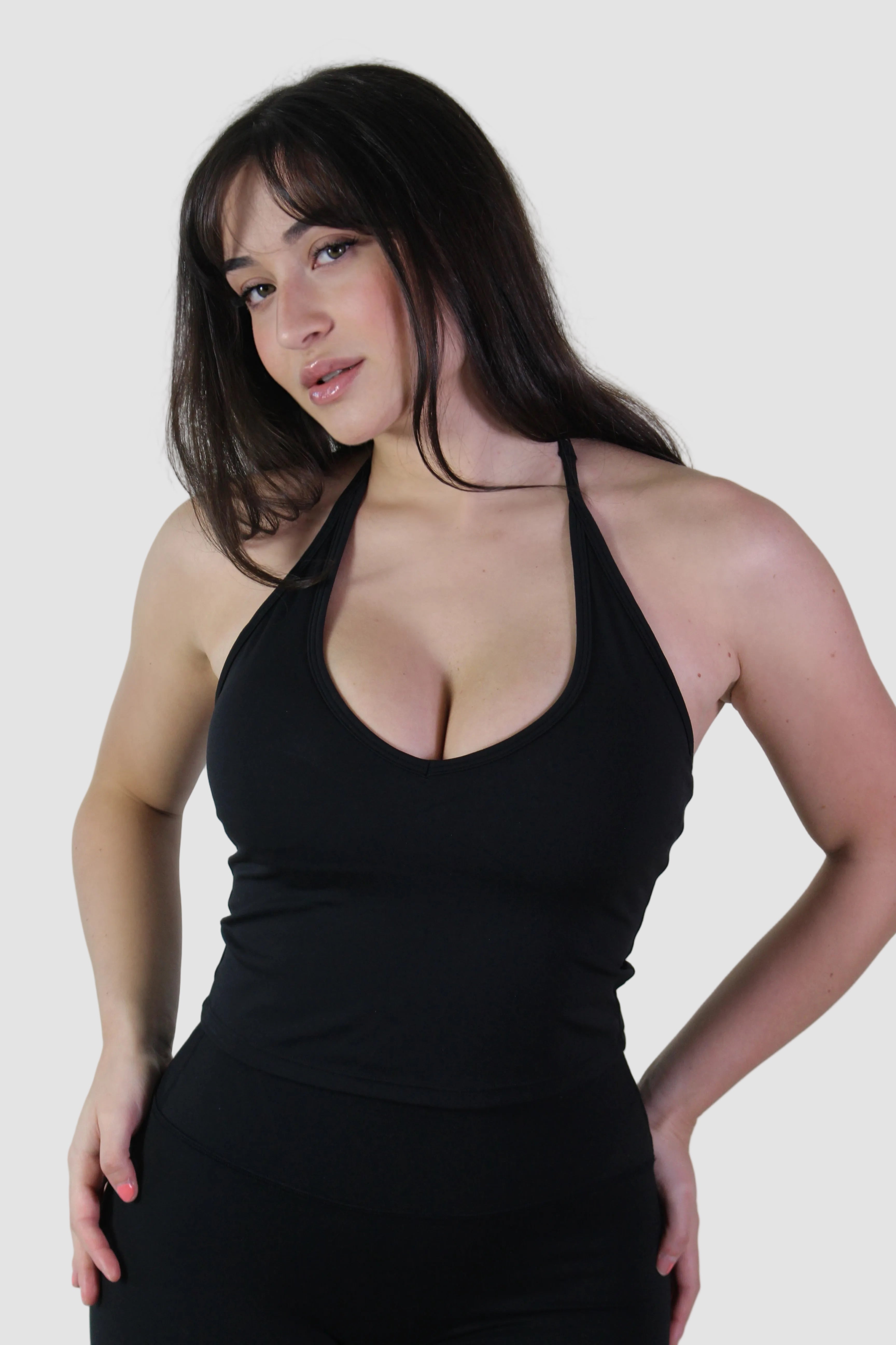 Woman wearing a black halter neck top against a plain background