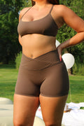 Back view of the AIVVIA NOVA shorts in mocha brown, highlighting the sculpting heart-shaped seam that contours and lifts the glutes. Designed with a seamless front and high-waisted crossover waistband, these 5-inch shorts are made from buttery soft, eco-friendly fabric for maximum comfort and support during workouts, yoga, Pilates, and daily wear.