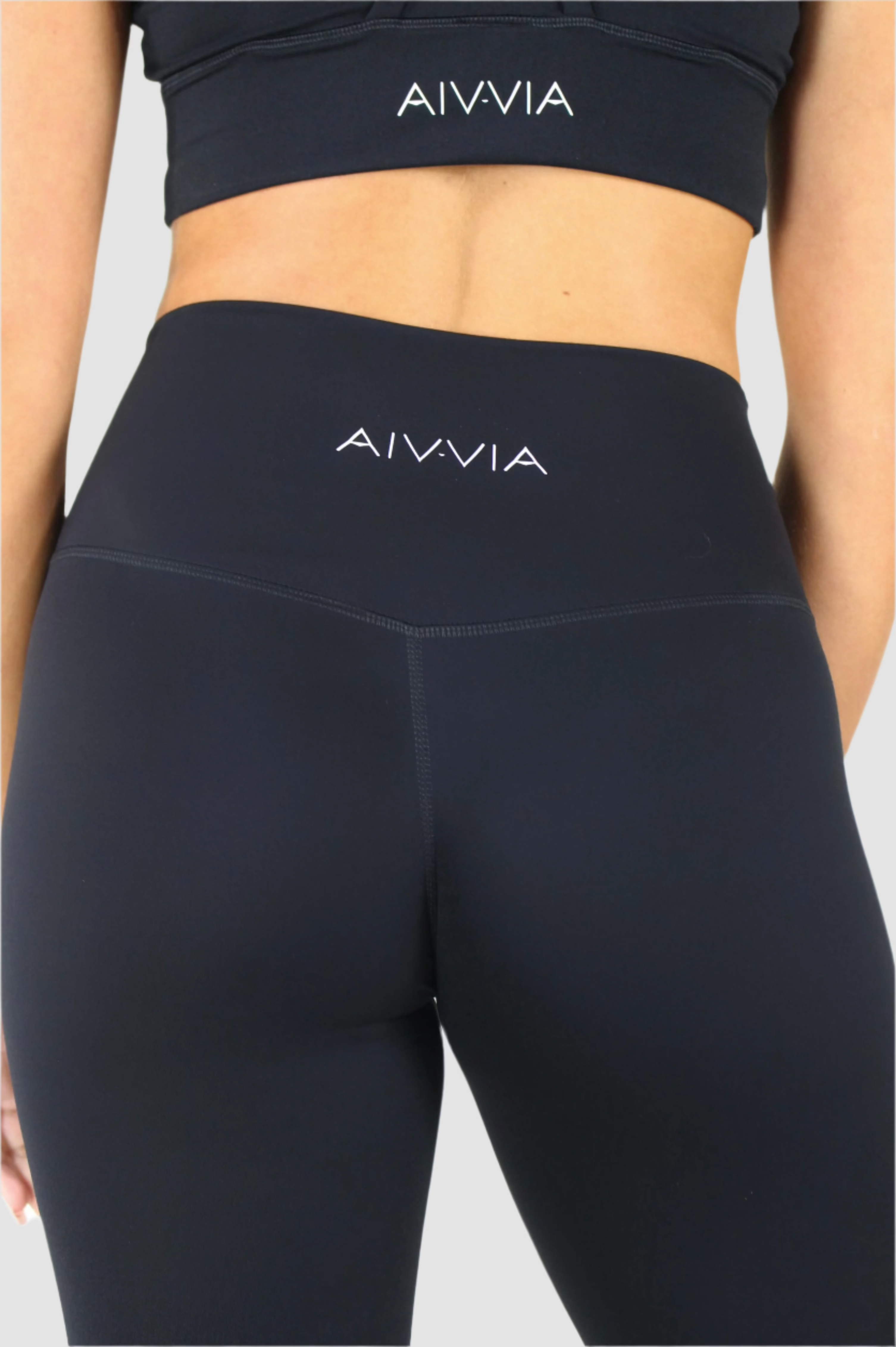 Back view of black Aivvia Athletics high-waisted flare pants with subtle logo detail at waistband.

