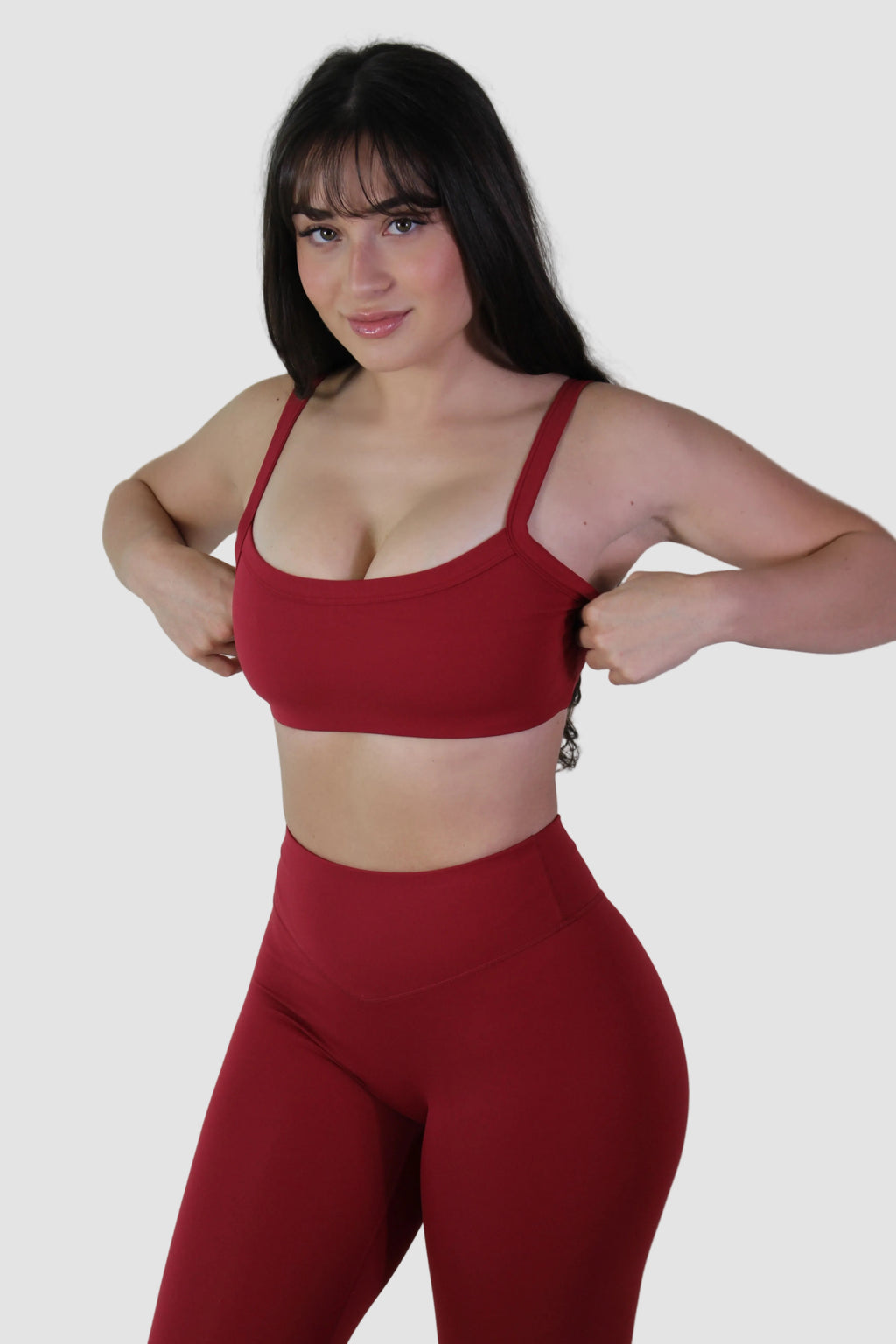Woman wearing a red sports bra and leggings against a plain background