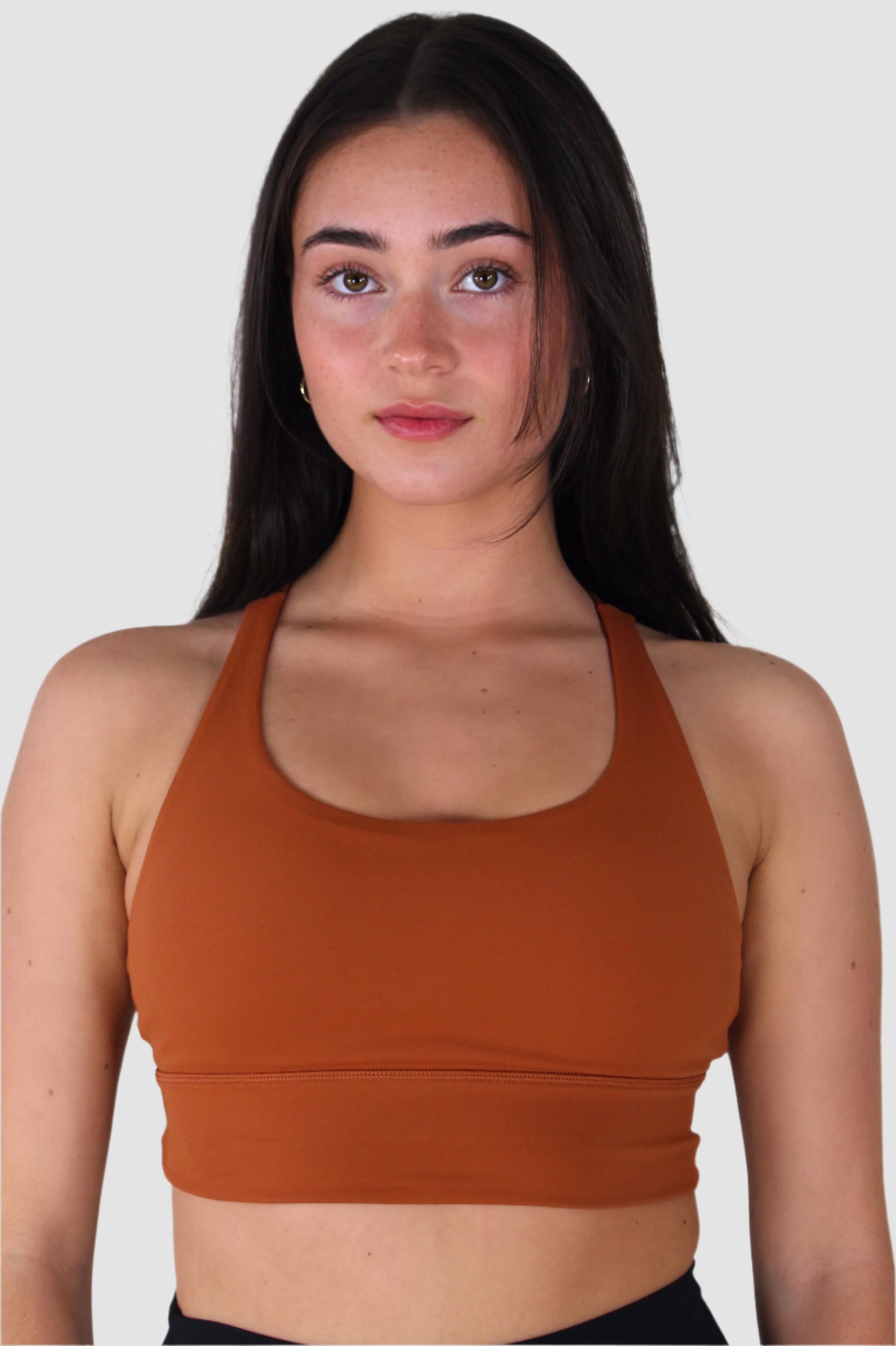 Side-back view of rust-colored Aivvia Athletics sports bra with crisscross strap detailing.