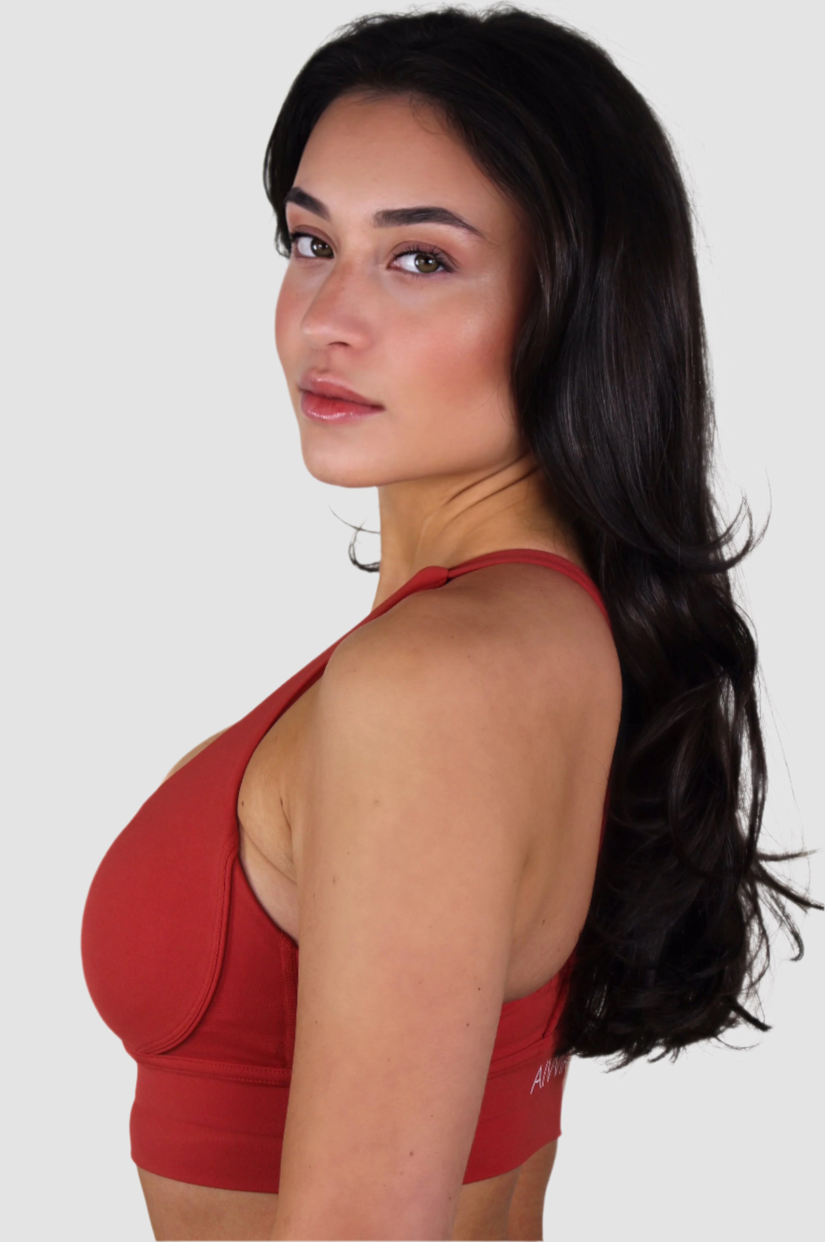 Side view of red Aivvia Athletics sports bra, showing wide straps and supportive contour design.