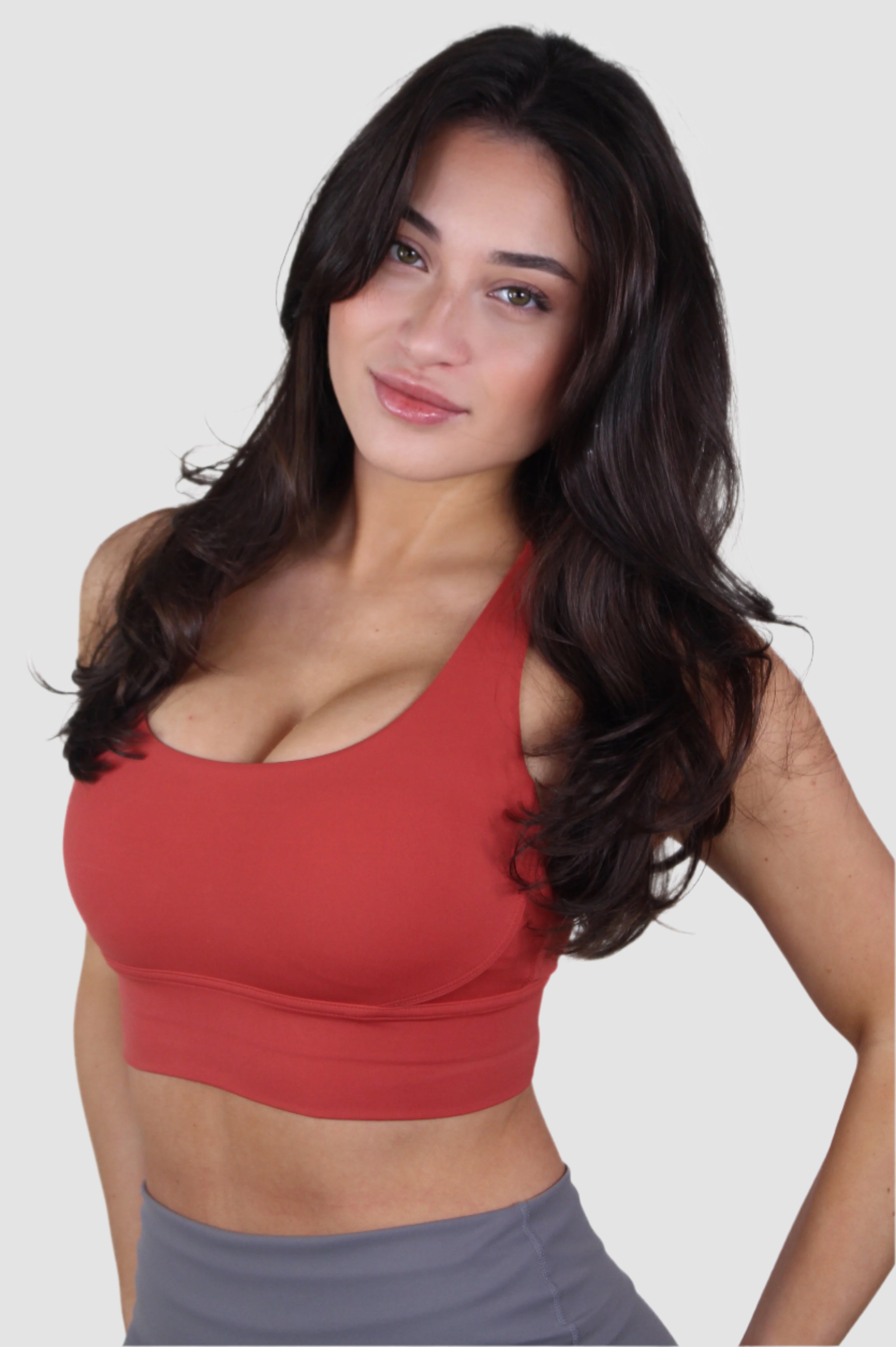 Angled front view of red Aivvia Athletics sports bra paired with gray leggings, highlighting activewear style.