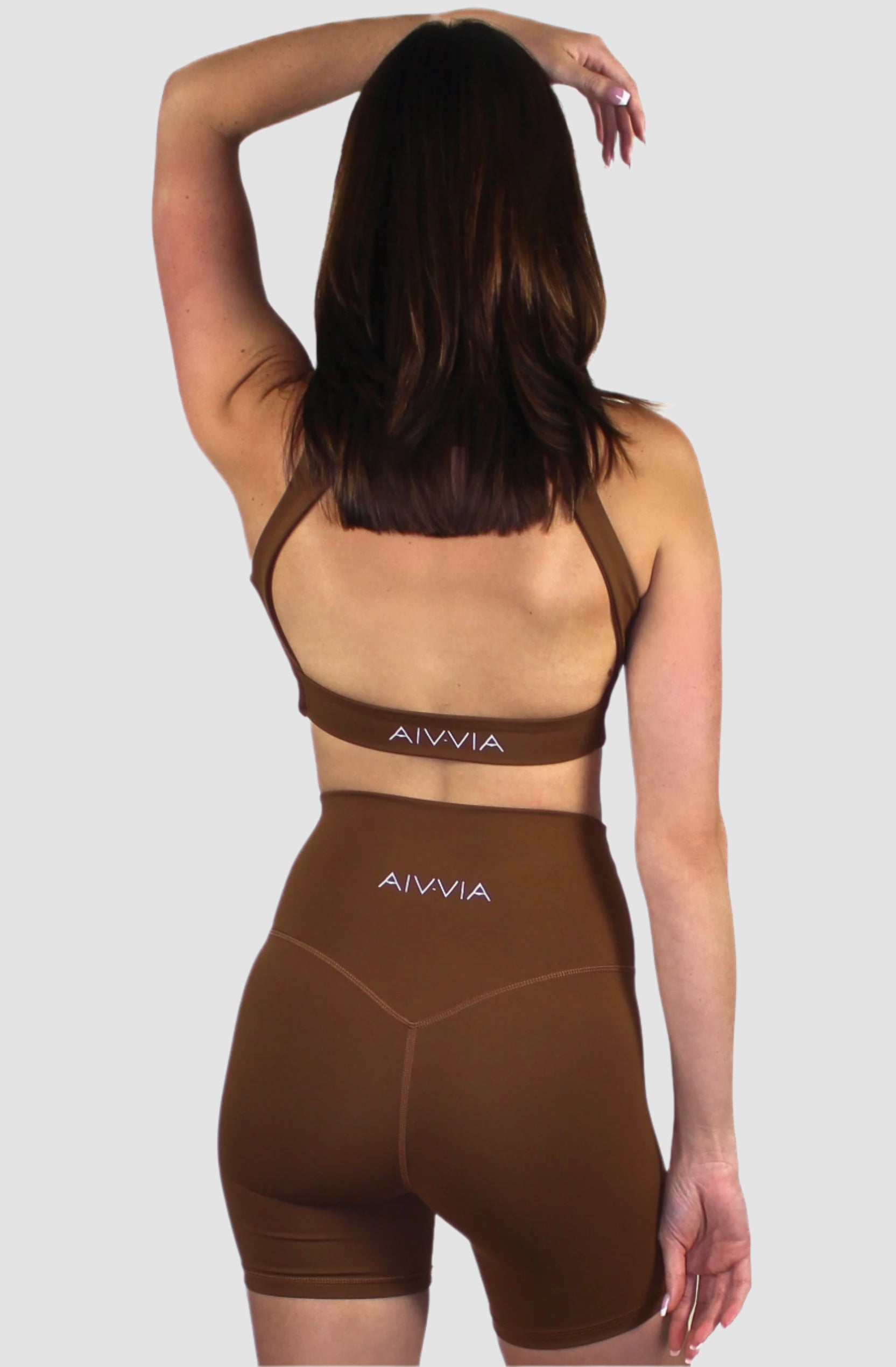 Back view of the mocha brown activewear set, showing racerback bra straps and logo detail on the shorts.