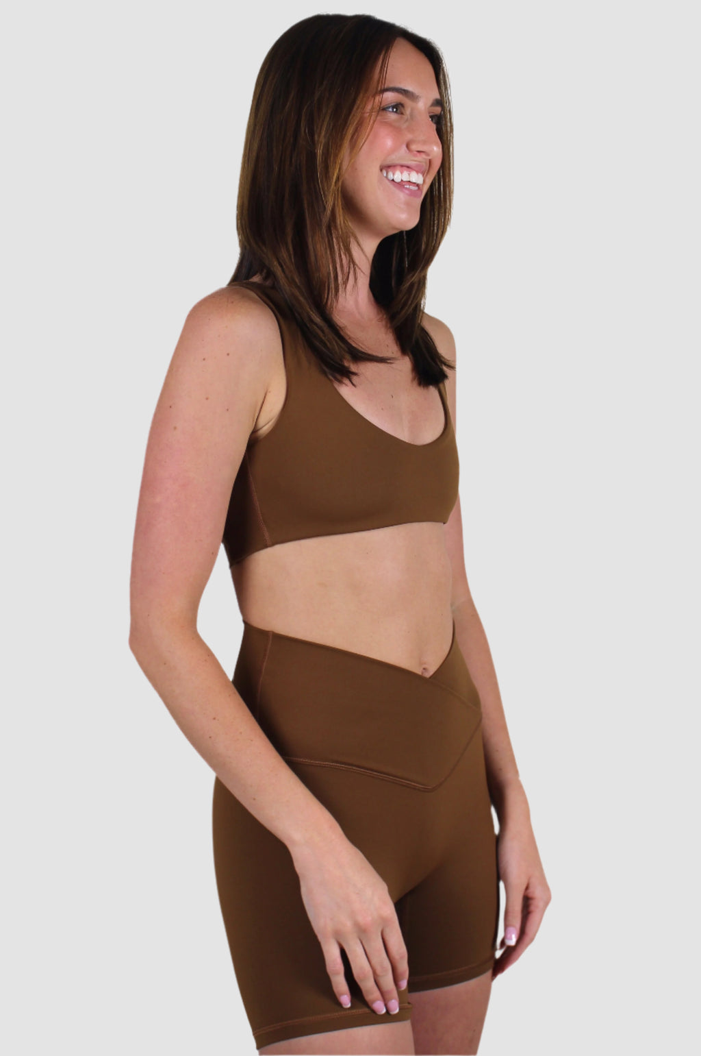 Side view of the mocha brown activewear set, highlighting the curved underbust design of the bra and the V-cut waistband.