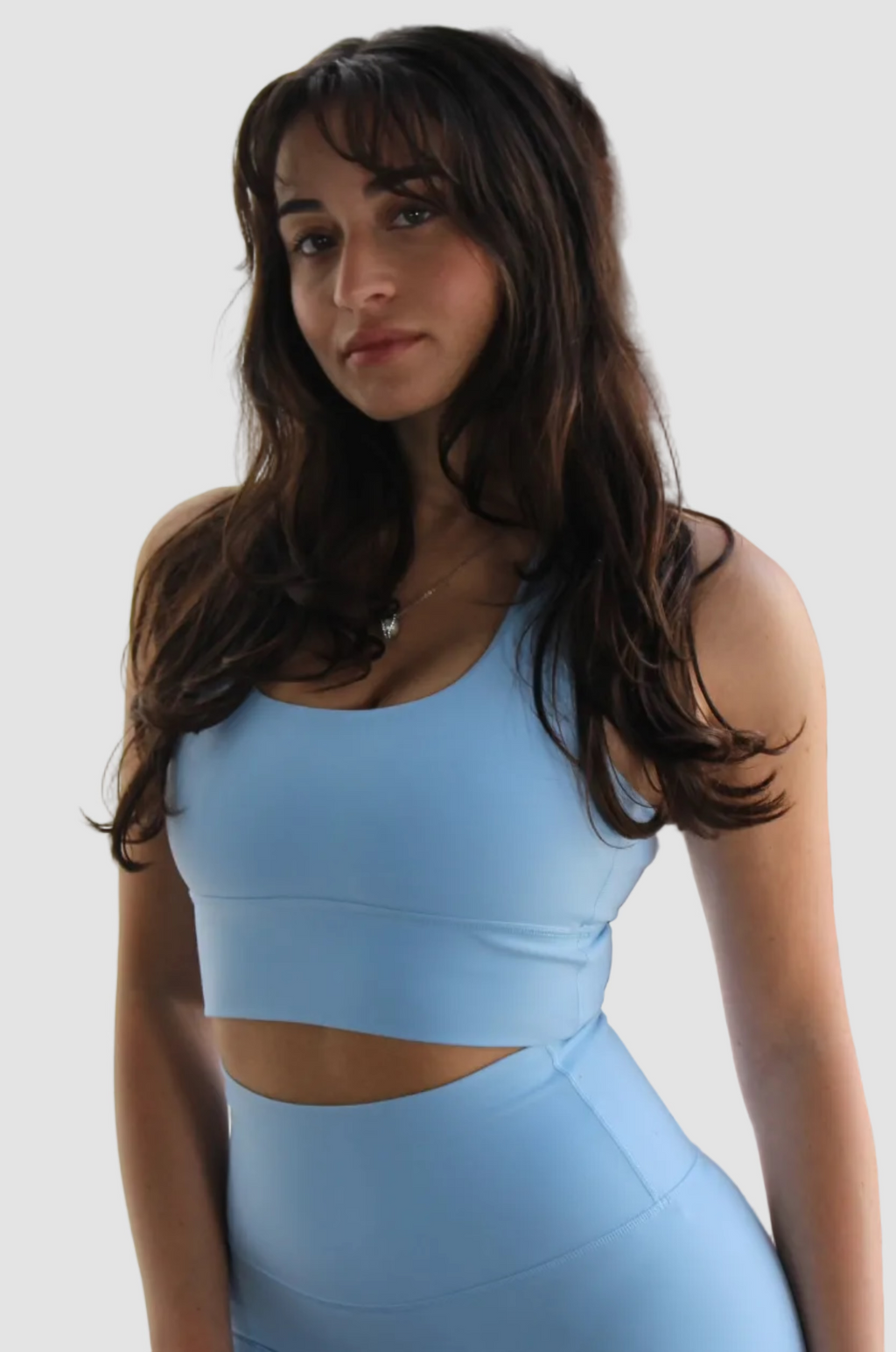 Woman wearing Aivvia Athletics light blue sports bra, showcasing front fit and support in a candid, natural light setting.