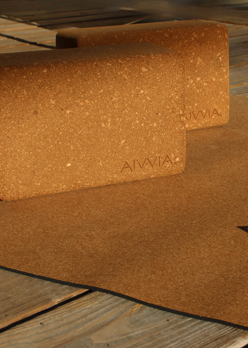 Close-up of two cork yoga blocks resting on a cork yoga mat with sunlight highlighting the texture.