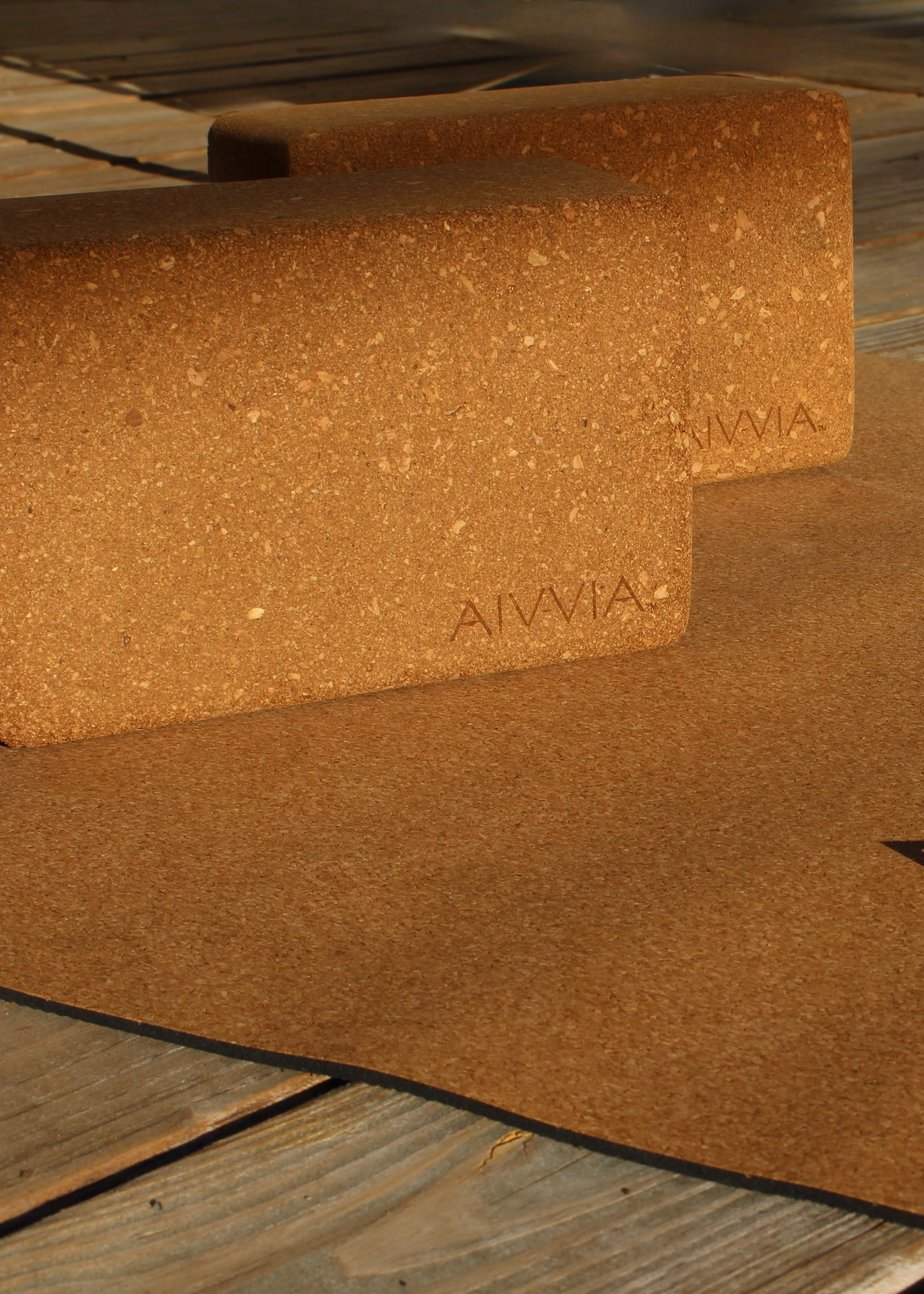 Close-up of two cork yoga blocks resting on a cork yoga mat with sunlight highlighting the texture.
