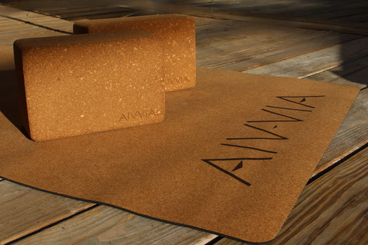 Close-up of two cork yoga blocks resting on a cork yoga mat with sunlight highlighting the texture.