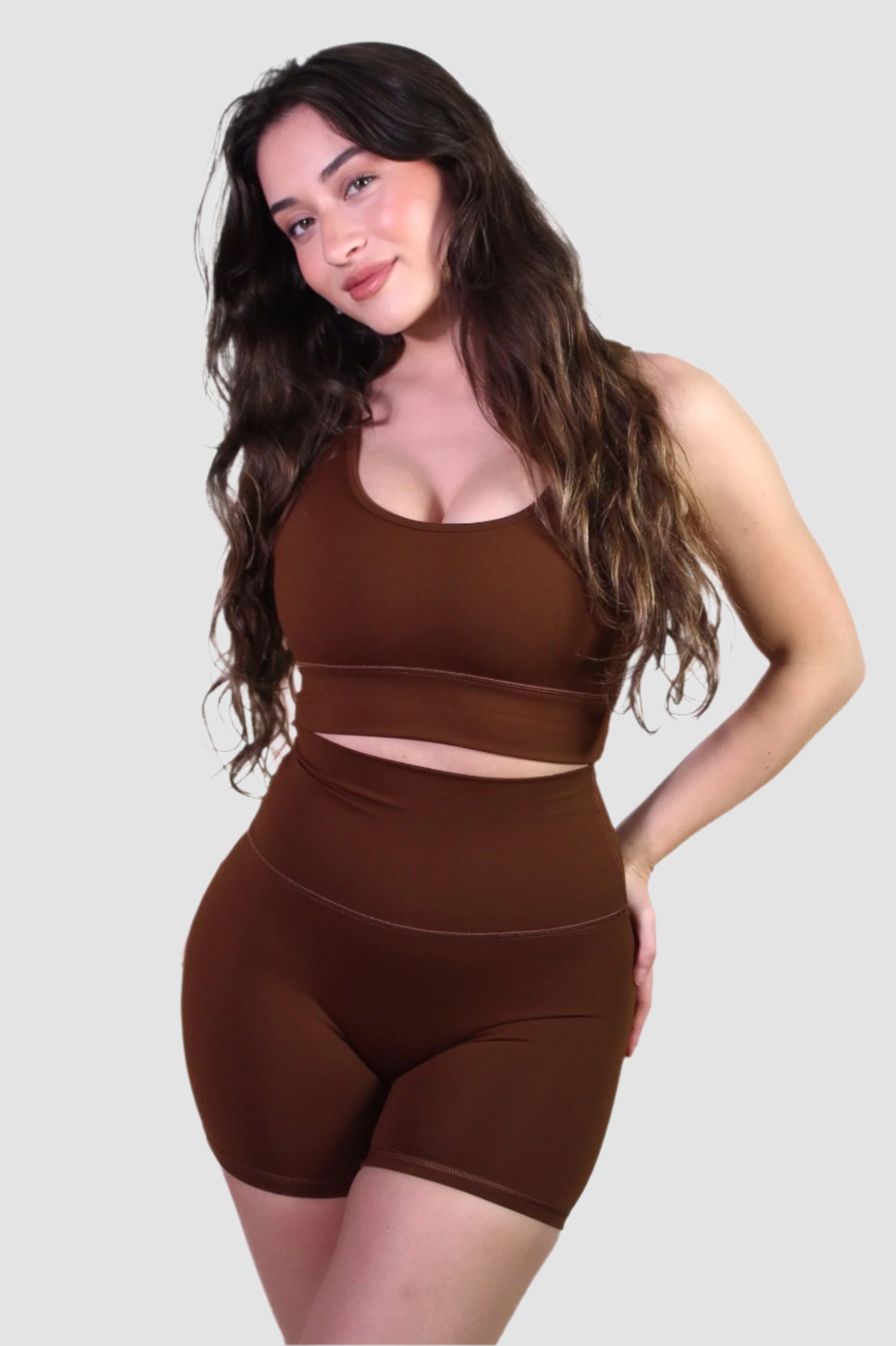 Angled front view of the chocolate brown activewear set, showing the sleek silhouette of the scoop-neck bra and matching biker shorts.