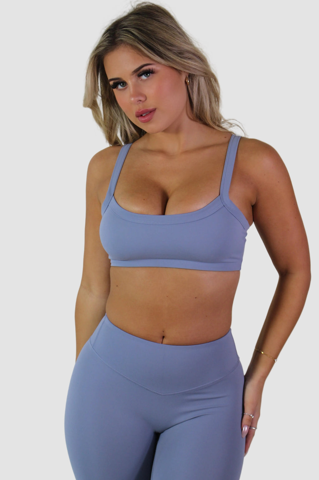 Woman wearing a blue sports bra and leggings against a plain background