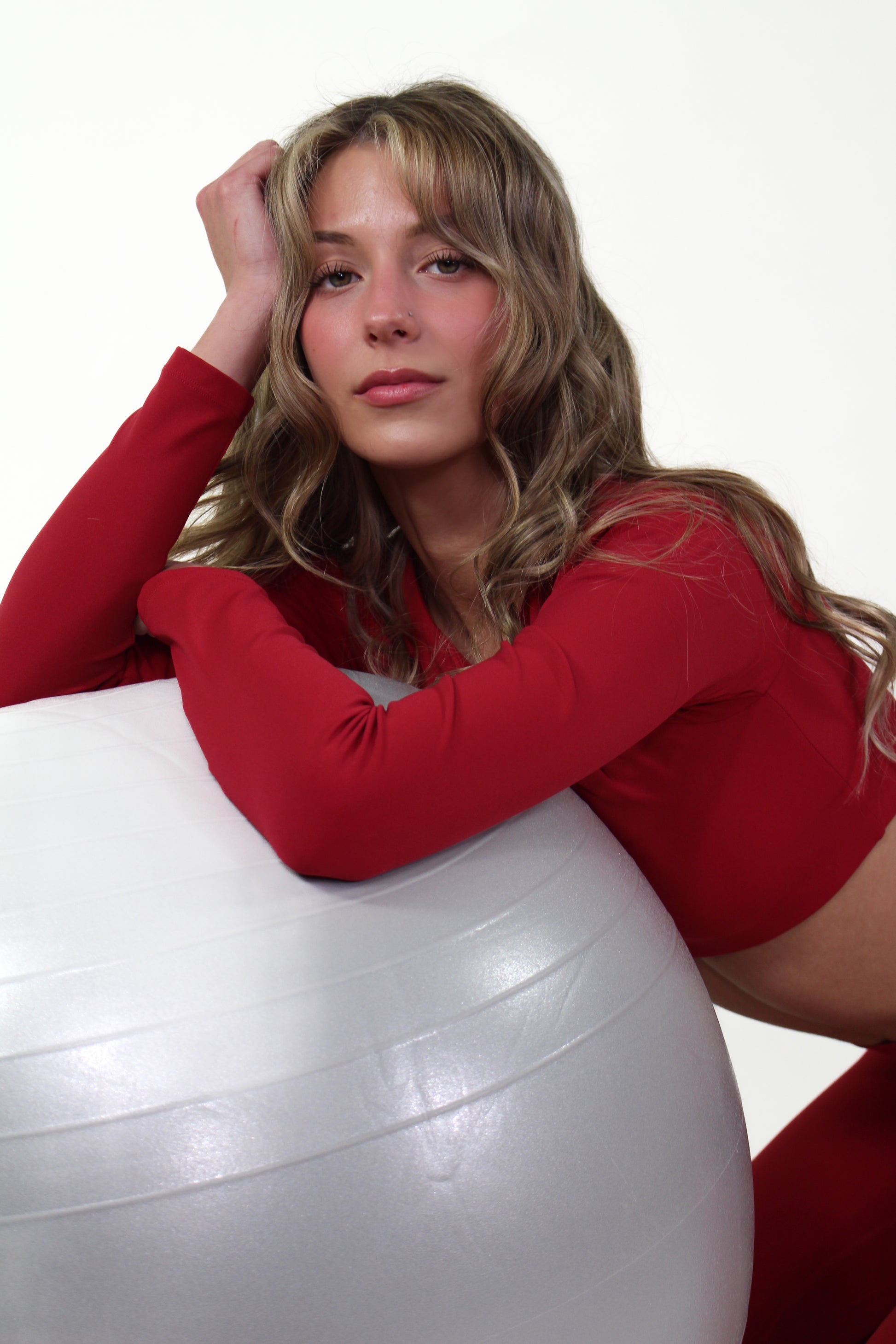 Woman wearing Aivvia Athletics red long sleeve sports bra with scoop neckline and cropped fit for active performance.