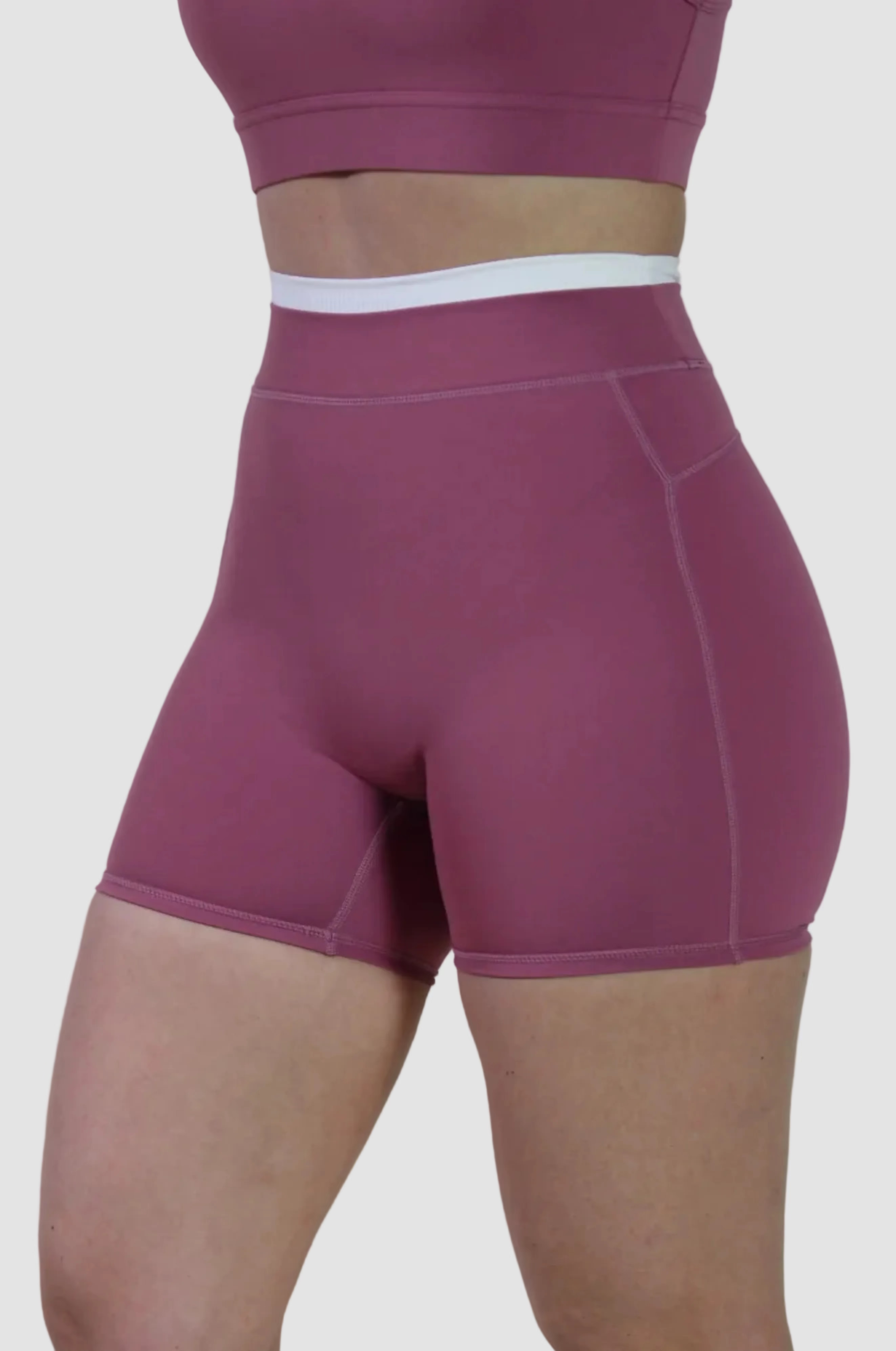 Person wearing maroon athletic shorts and top on a plain background