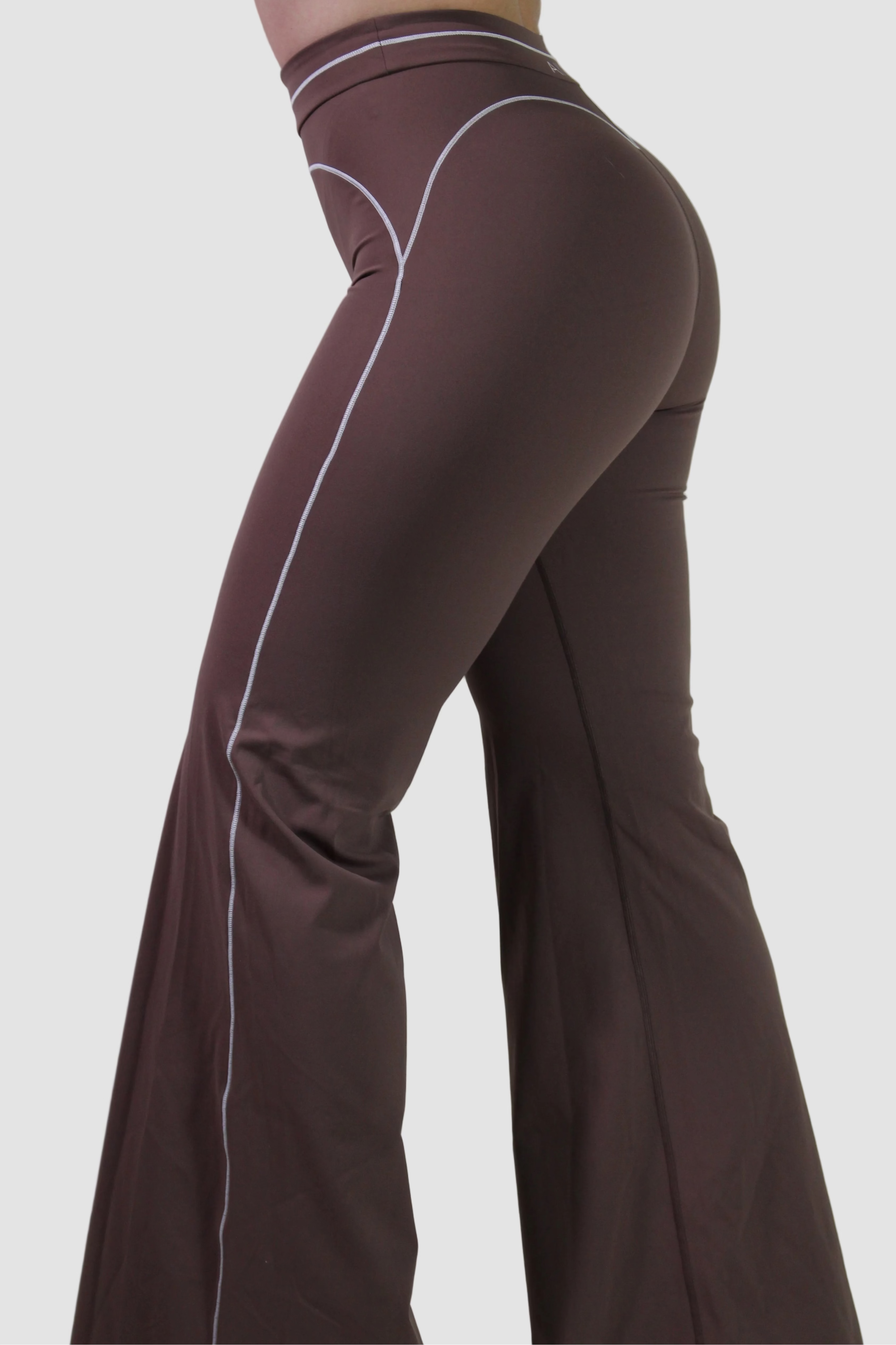 Side profile of a woman wearing espresso brown high-waisted workout shorts, highlighting the supportive waistband for gym, pilates, and active training.