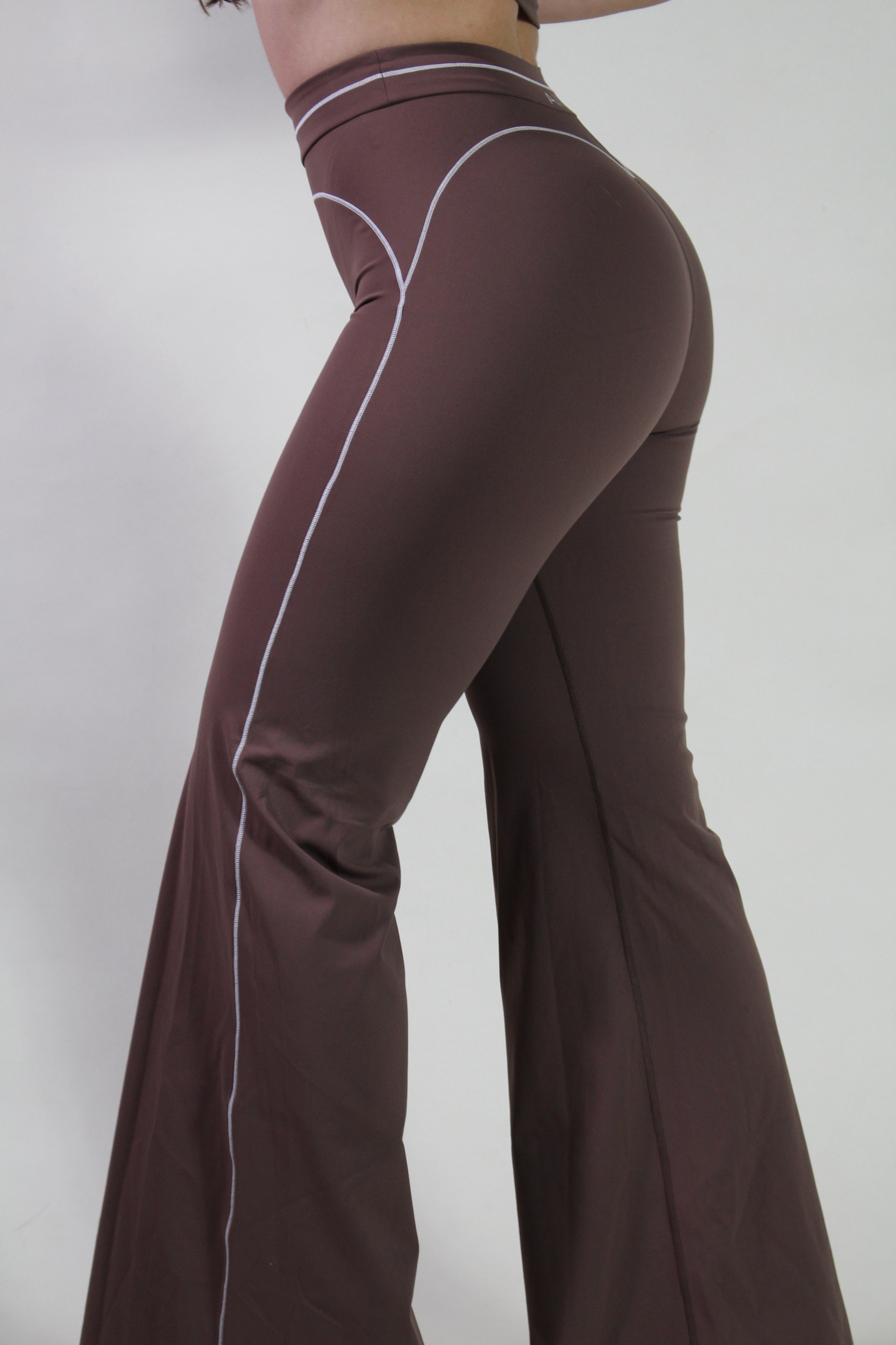 Side profile of a woman wearing espresso brown high-waisted workout shorts, highlighting the supportive waistband for gym, pilates, and active training.