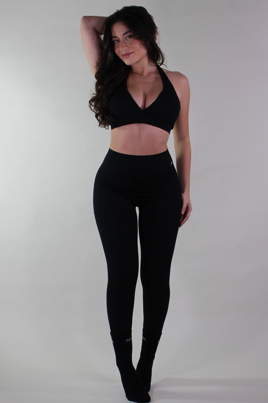 Woman wearing a black sports bra and leggings on a plain background