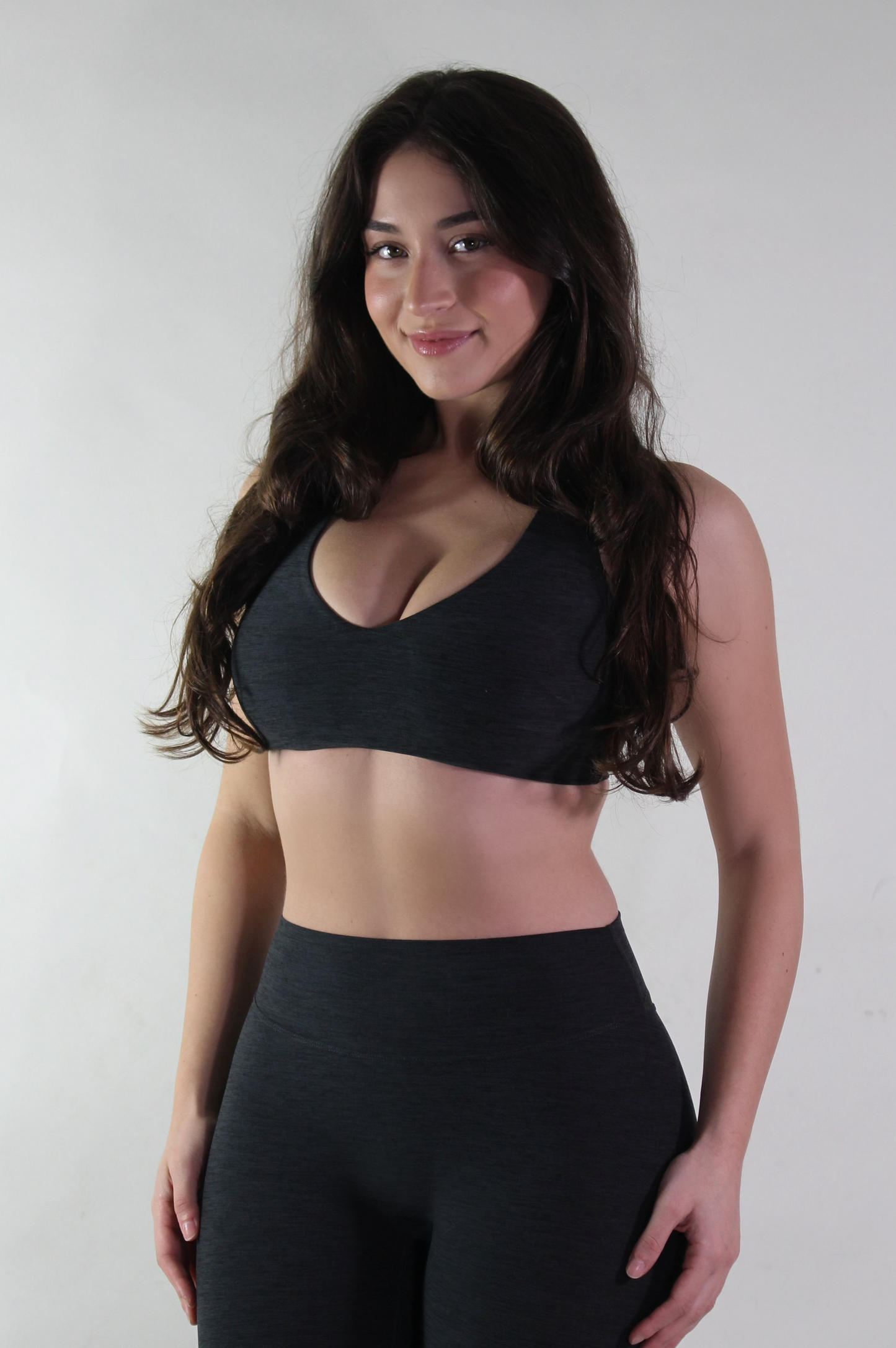 Woman wearing a black sports bra and leggings against a white background
