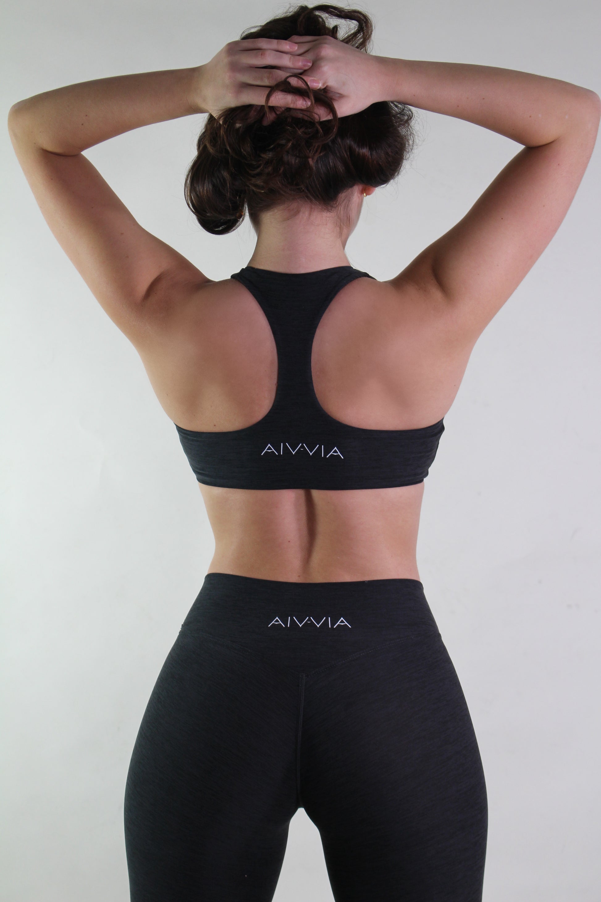 Person wearing black AIVVIA sports bra and leggings against a white background