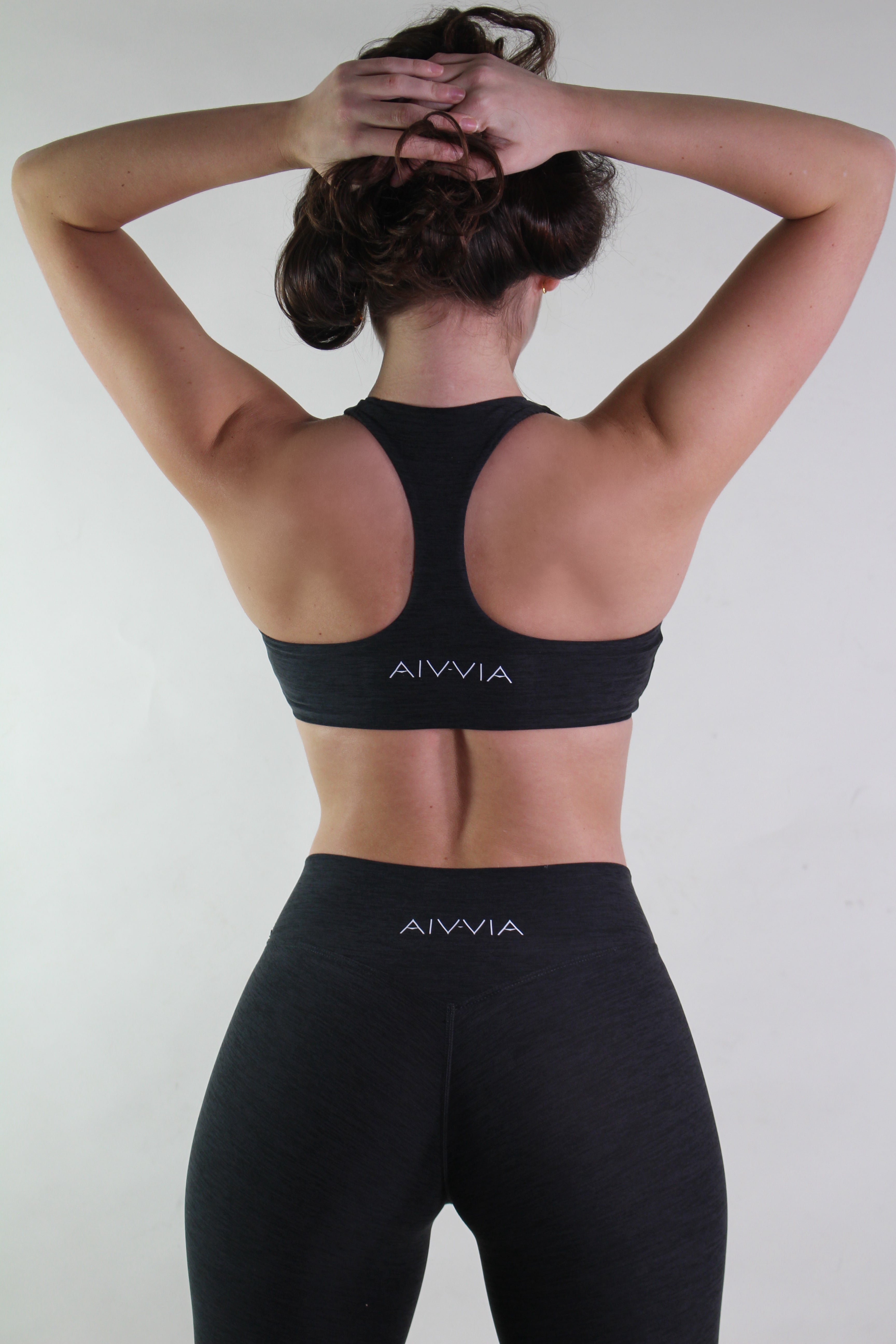 Person wearing black AIVVIA sports bra and leggings against a white background
