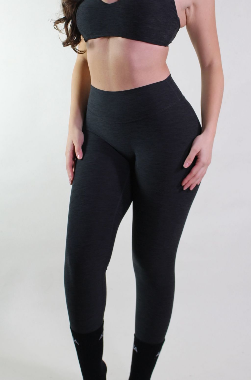 Woman wearing a black sports bra and leggings on a white background