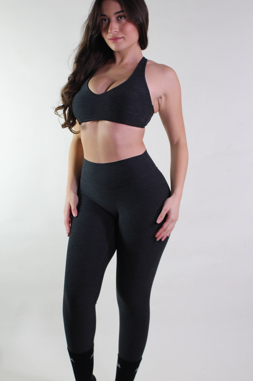Woman wearing a black sports bra and leggings on a white background
