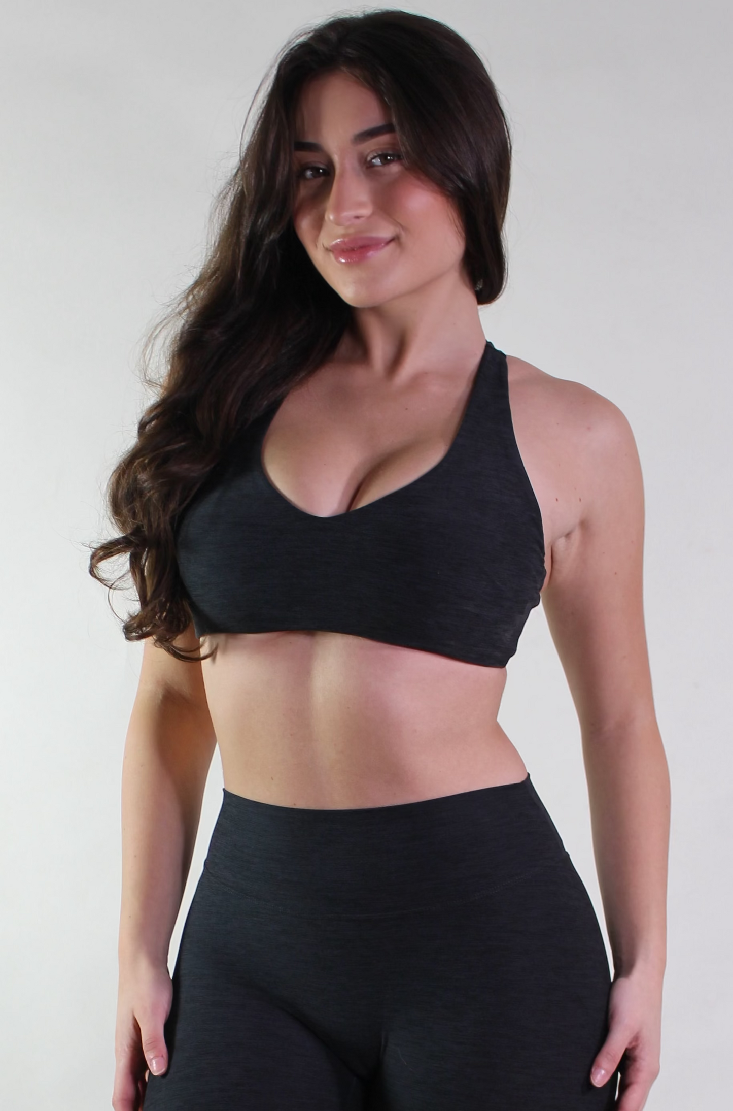 Woman wearing a black sports bra and leggings on a white background