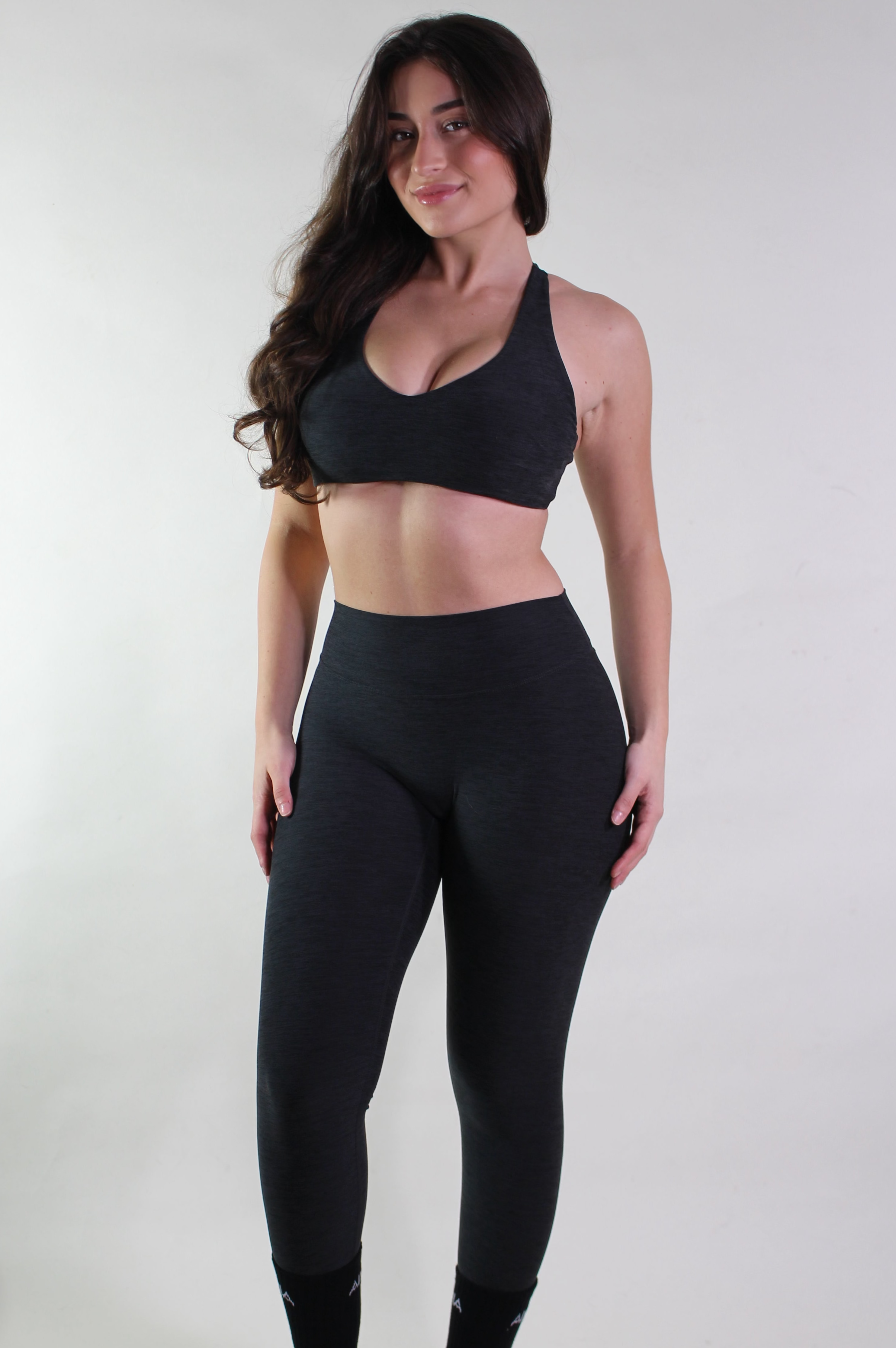 Woman wearing a black sports bra and leggings on a white background