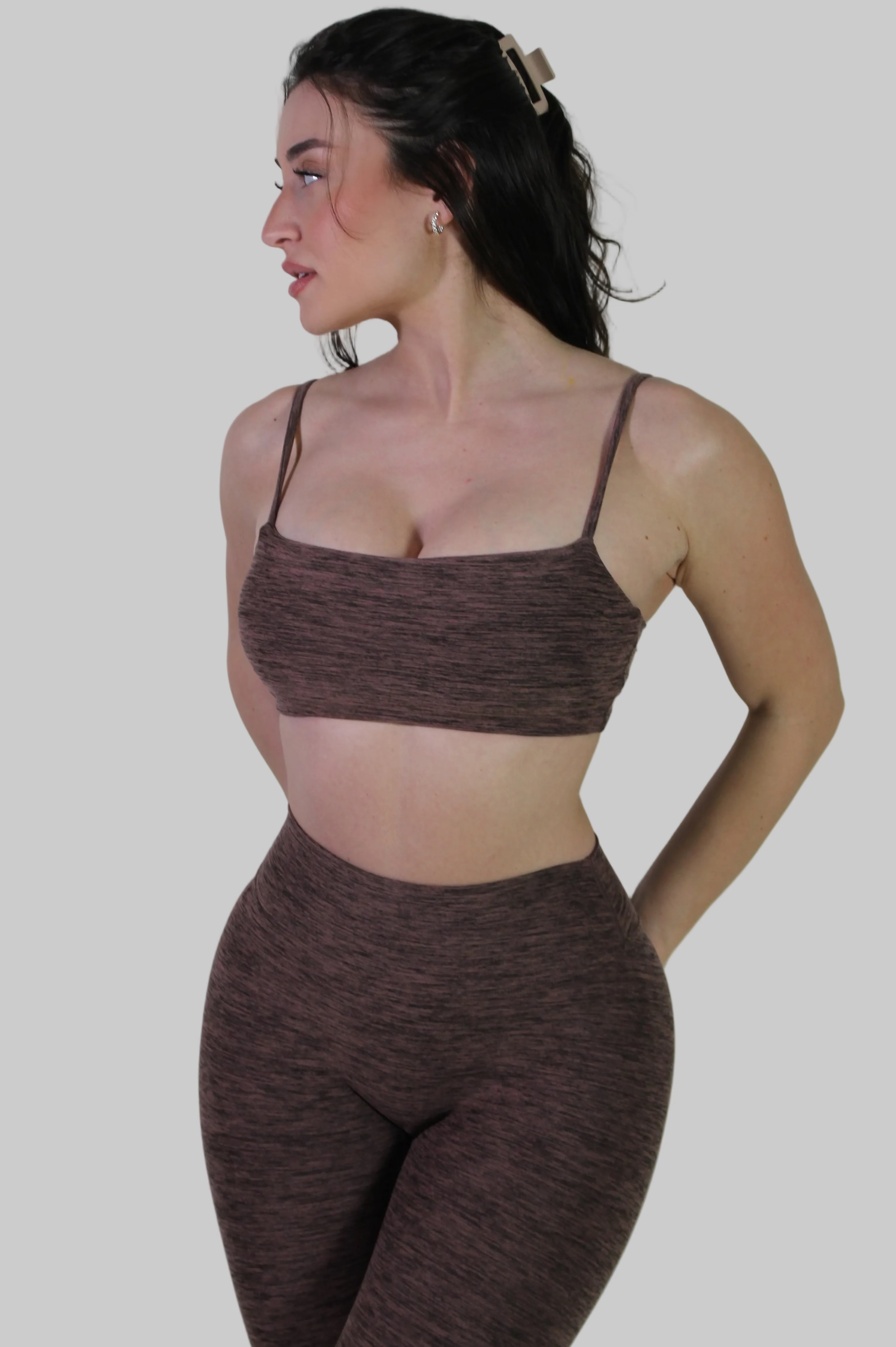 Woman wearing a brown textured sports bra and leggings set against a plain background