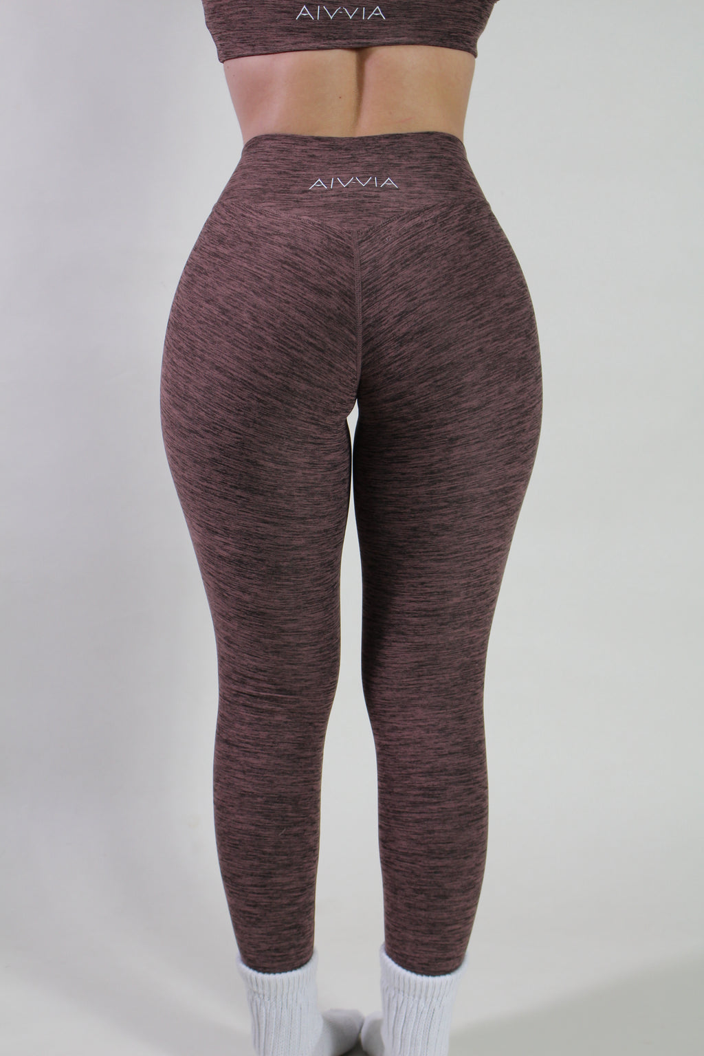 Rear view of Aivvia Athletics marl espresso leggings highlighting the V-shaped glute-contouring seam and the silver logo on the waistband.
