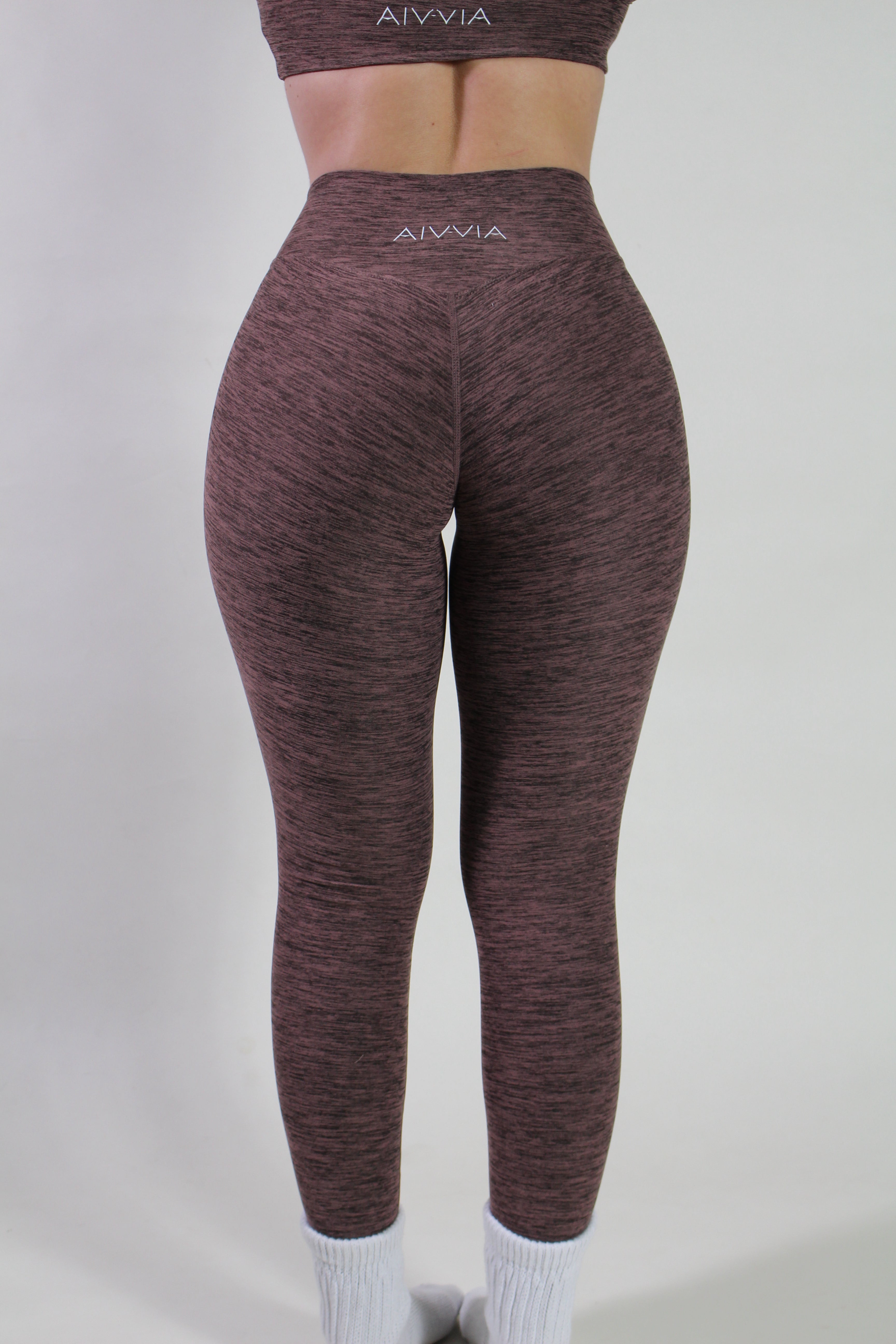 Rear view of Aivvia Athletics marl espresso leggings highlighting the V-shaped glute-contouring seam and the silver logo on the waistband.