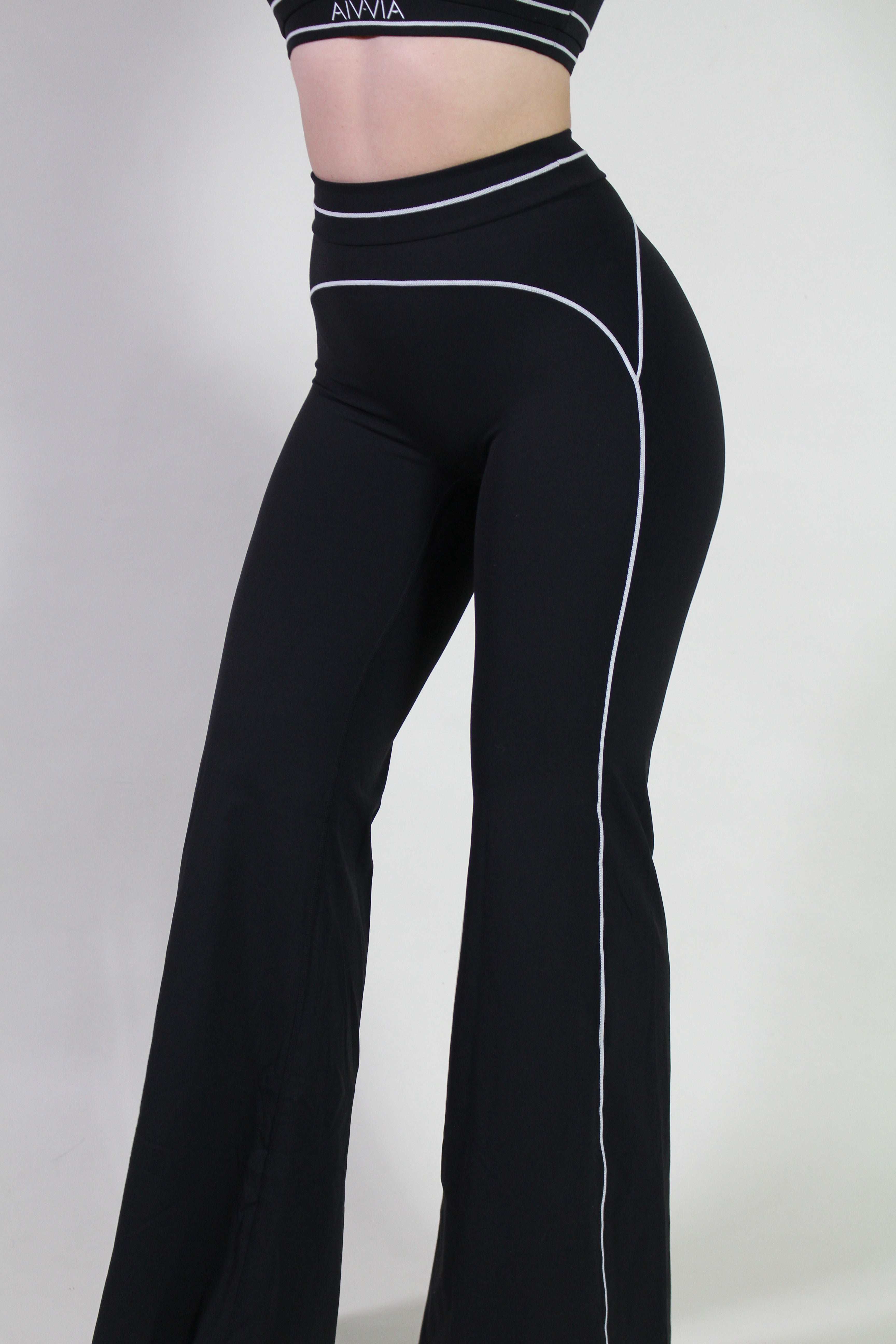 Side view of Aivvia Athletics black yoga pants showing sculpting seam details and flare leg, perfect for gym, pilates, and yoga sessions.