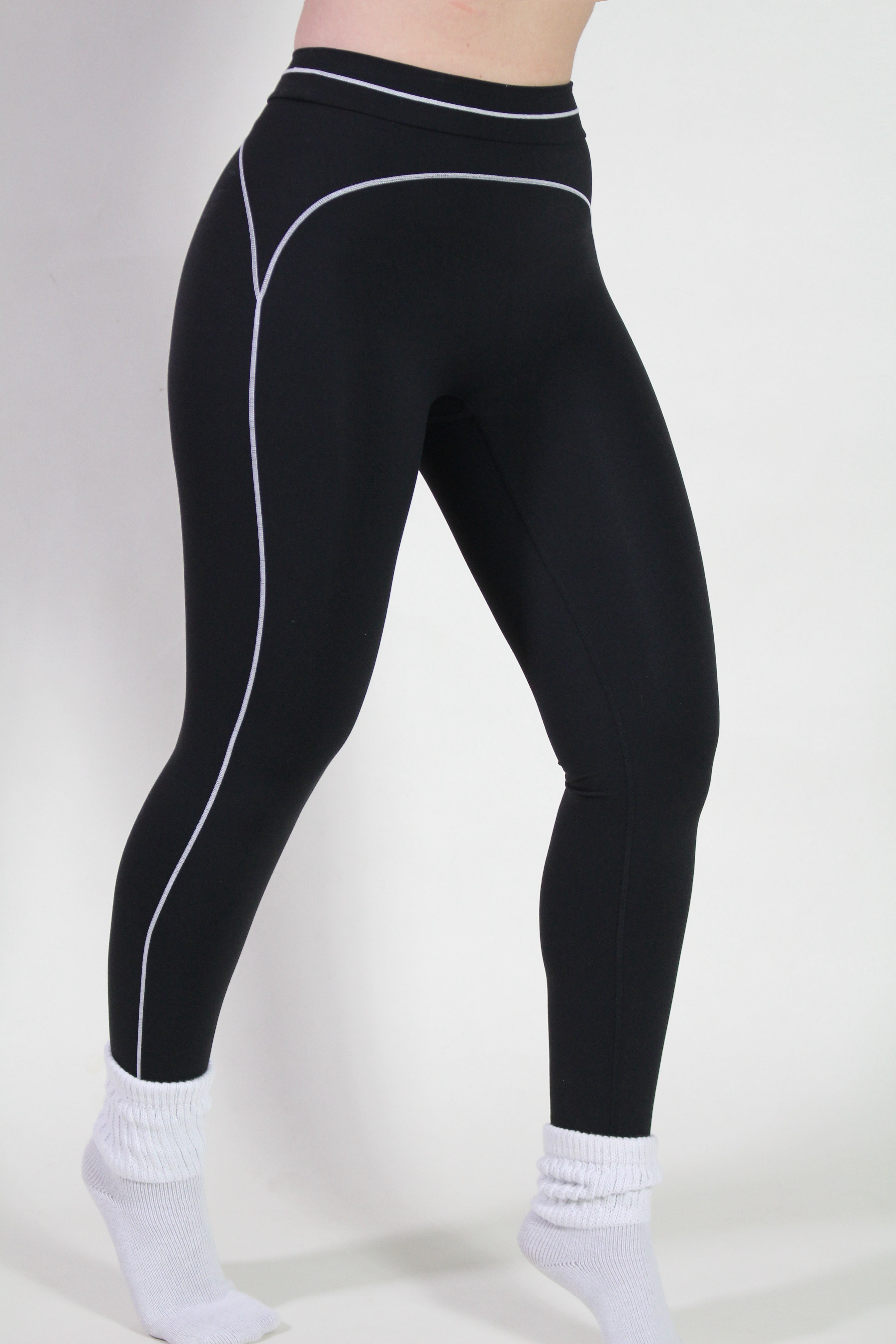 Side detail of black performance fabric showing underband and seam construction of leggings, designed for gym, pilates, and active training.