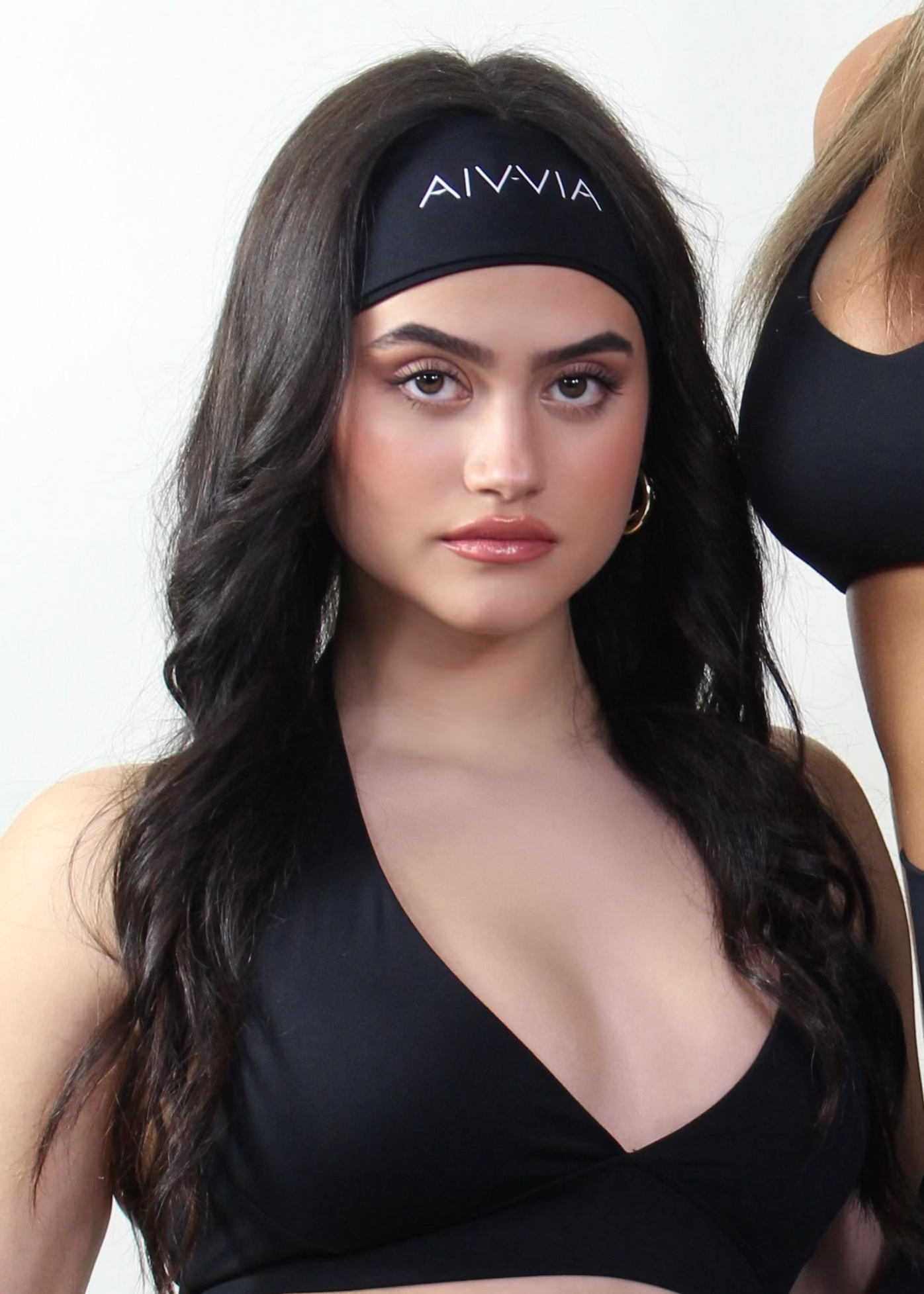 Woman wearing a black sports bra and leggings with 'AIVIVIA' branding.