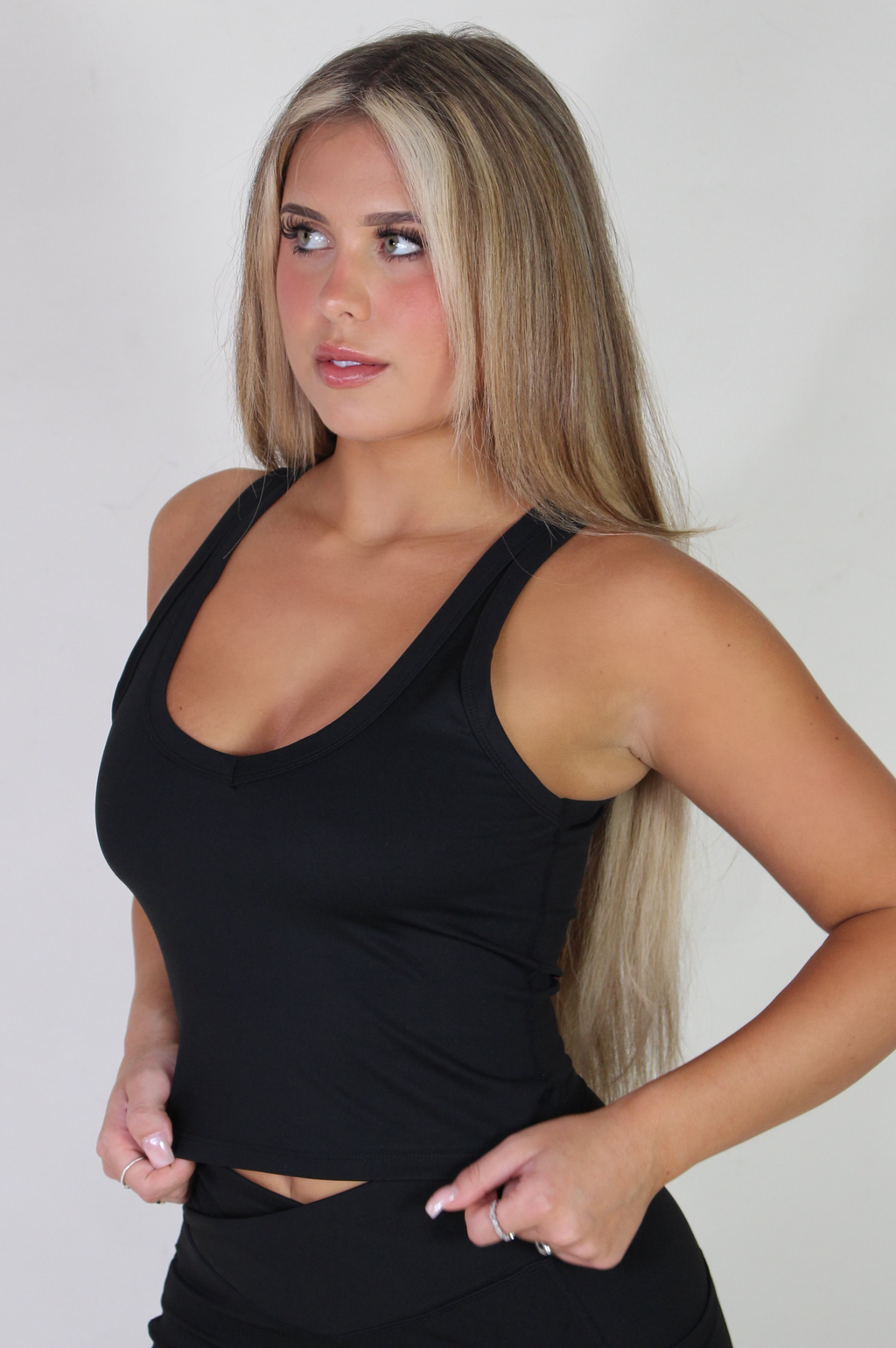 Front-facing view of a woman wearing the Aivvia Athletics black sculpt tank top, showcasing the scoop neckline and fitted torso for activewear workouts.