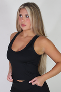 Front-facing view of a woman wearing the Aivvia Athletics black sculpt tank top, showcasing the scoop neckline and fitted torso for activewear workouts.