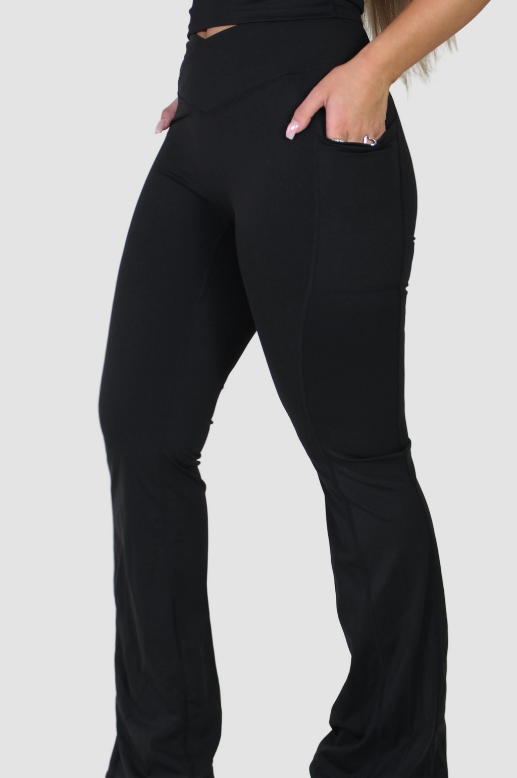 Side profile of Aivvia Athletics black sculpt pants, showcasing flared leg, sculpting fit, and convenient pocket detail.
