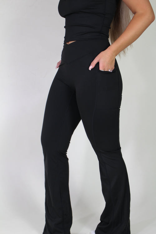 Side profile of Aivvia Athletics black sculpt pants, showcasing flared leg, sculpting fit, and convenient pocket detail.