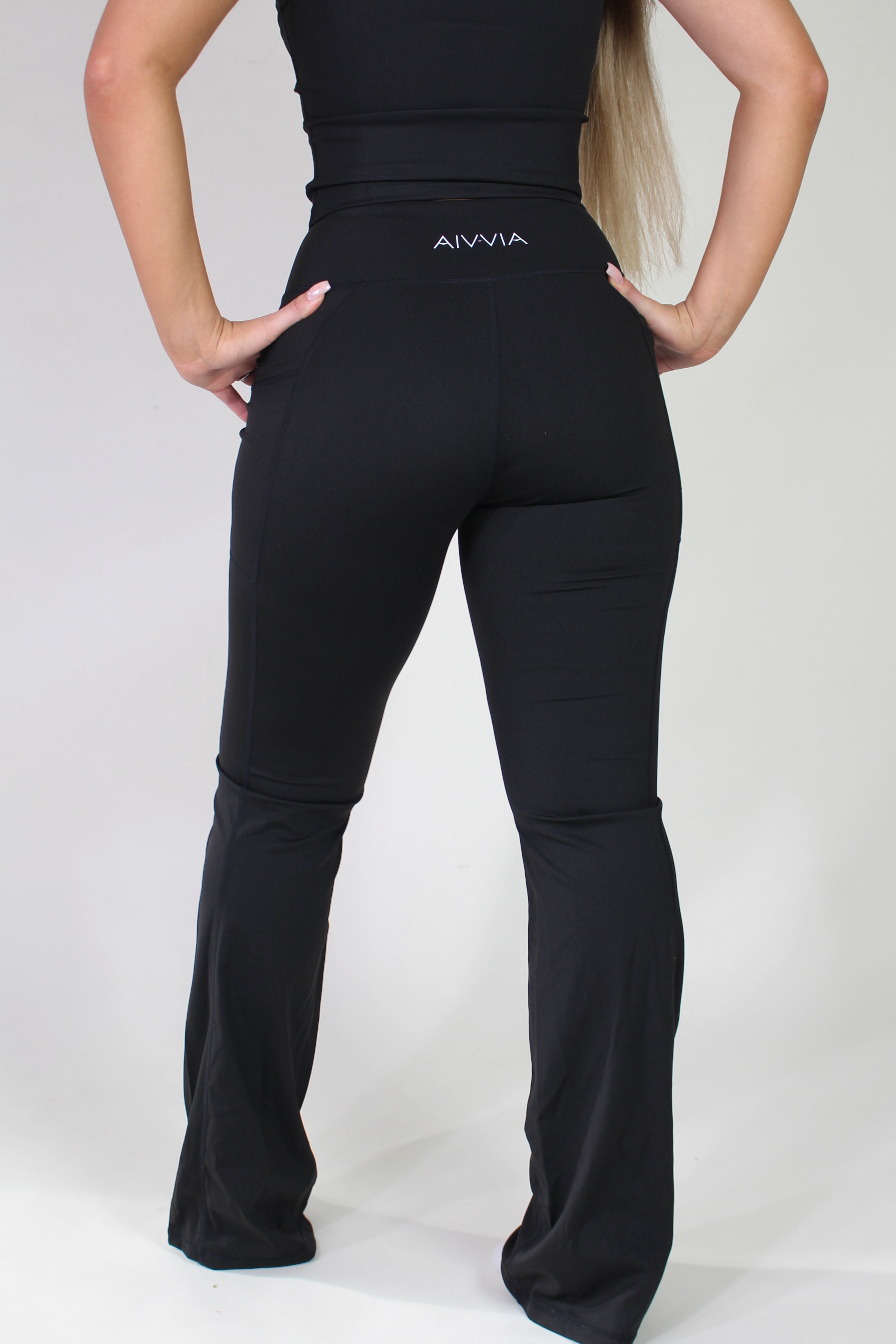 Full-length rear view of Aivvia Athletics sculpt pants, illustrating flared leg design, flattering silhouette, and practical pockets for activewear and athleisure looks.