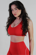 Woman wearing a red sports bra and leggings against a plain background