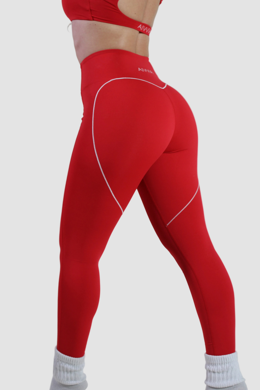 Angled rear view of Aivvia Athletics red high-waisted leggings with white heart-shaped buttock seam for sculpting fit.