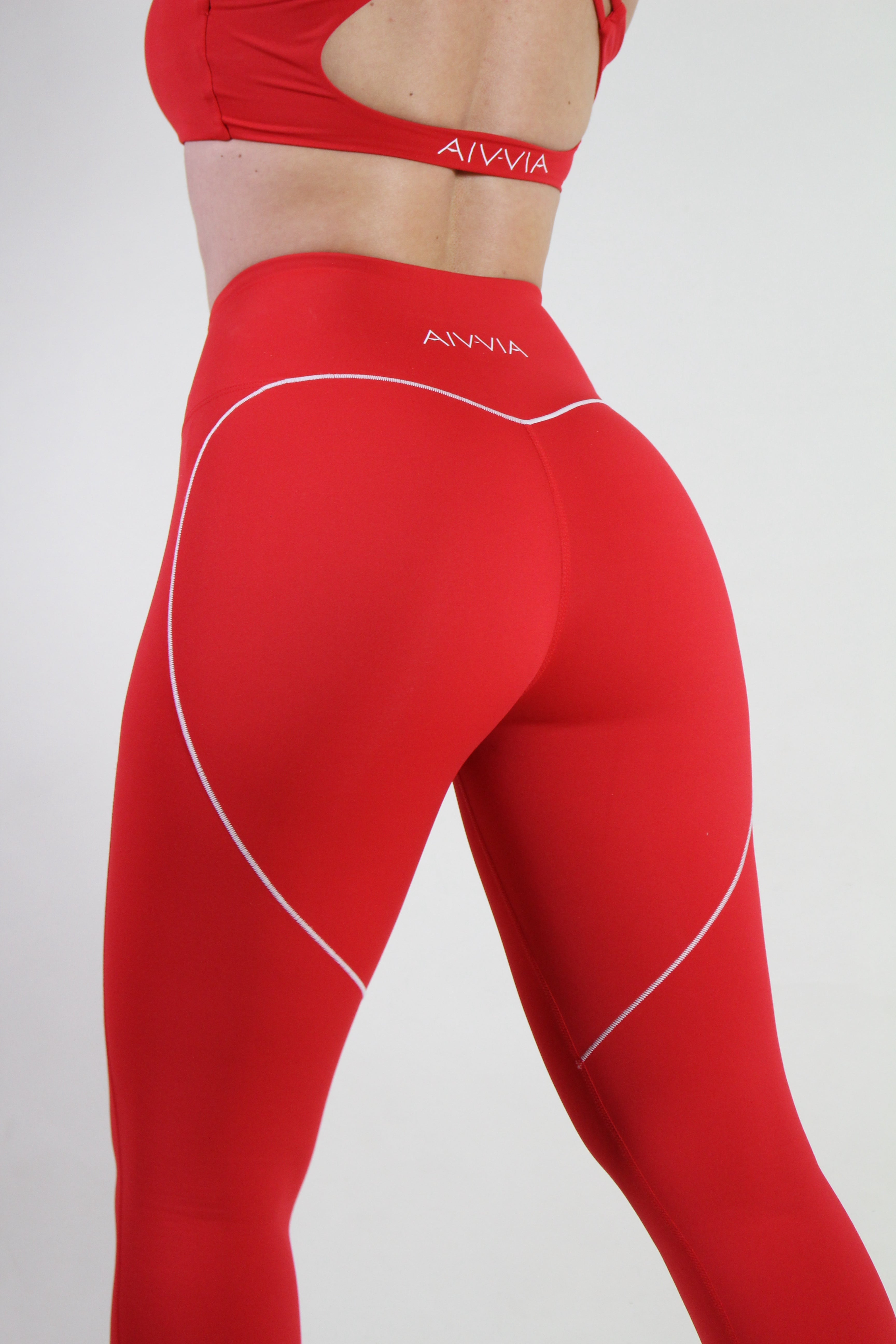 Close-up of Aivvia Athletics red leggings back, highlighting white heart seam and subtle logo for gym activewear.