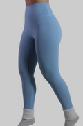 Woman wearing Aivvia Athletics baby blue high-waisted leggings, with smooth seamless front panel for gym and workout.