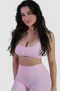Woman wearing Aivvia Athletics baby pink sports bra with scoop neckline and smooth compressive fit for gym and workouts.