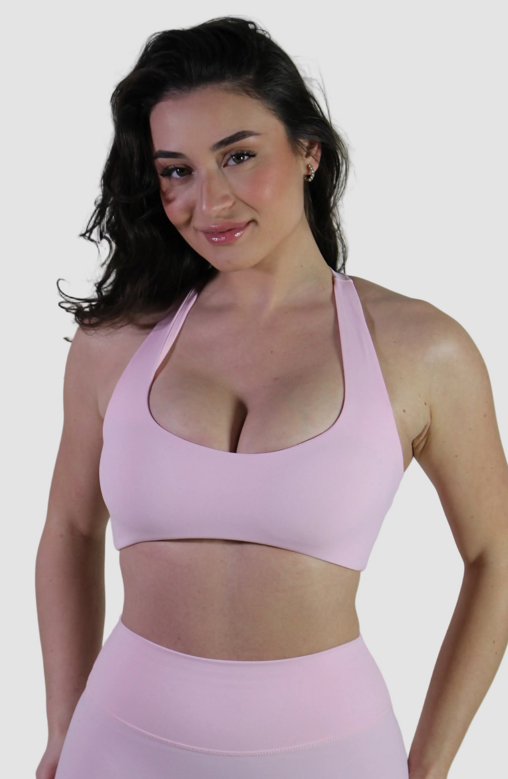 Woman wearing a pink sports bra and leggings against a plain background